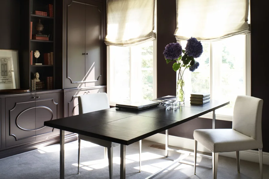 The dark wood built-ins provide ample storage while hiding unsightly ductwork. White chairs and draperies contrast to create a sense of formality in this home office. (Casey Design / Planning Group Inc. - photograph by Ted Yardwood)