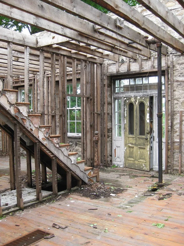 The original Italianate entry door and historically original frame with side lights and transom which we restored and reinstalled shown above post fire. Note the stairs that were removed to create the open concert/salon space.