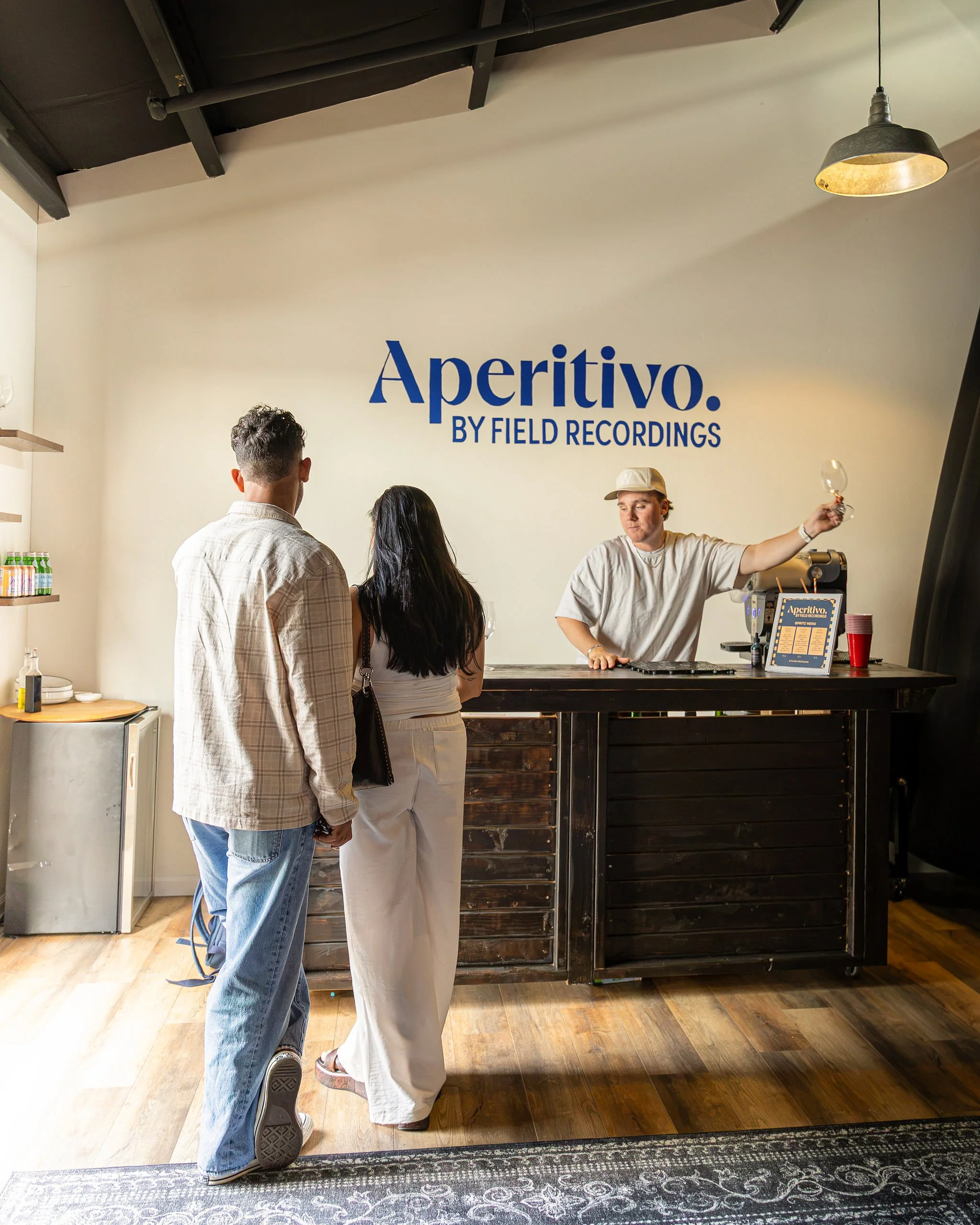 Jack pours a wine at the Aperitivo Bar, while two peole stand and wait.