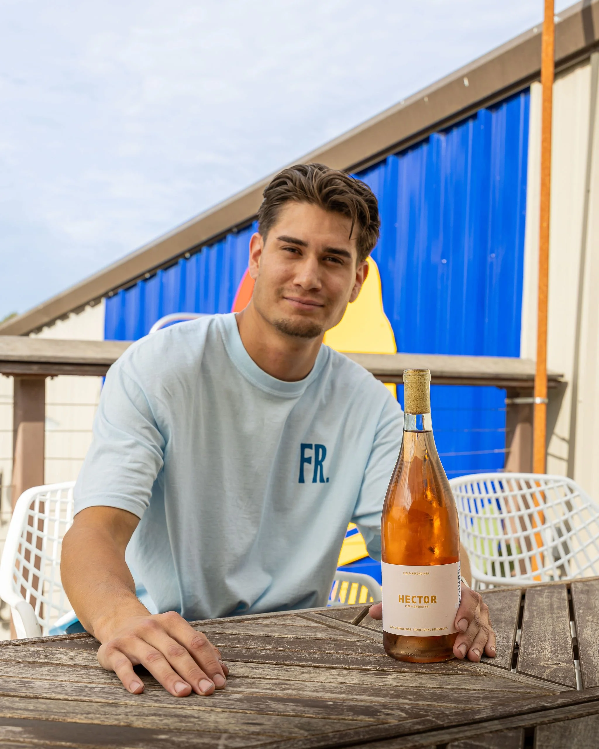 Hector sits at a patio table and poses with his rosé.