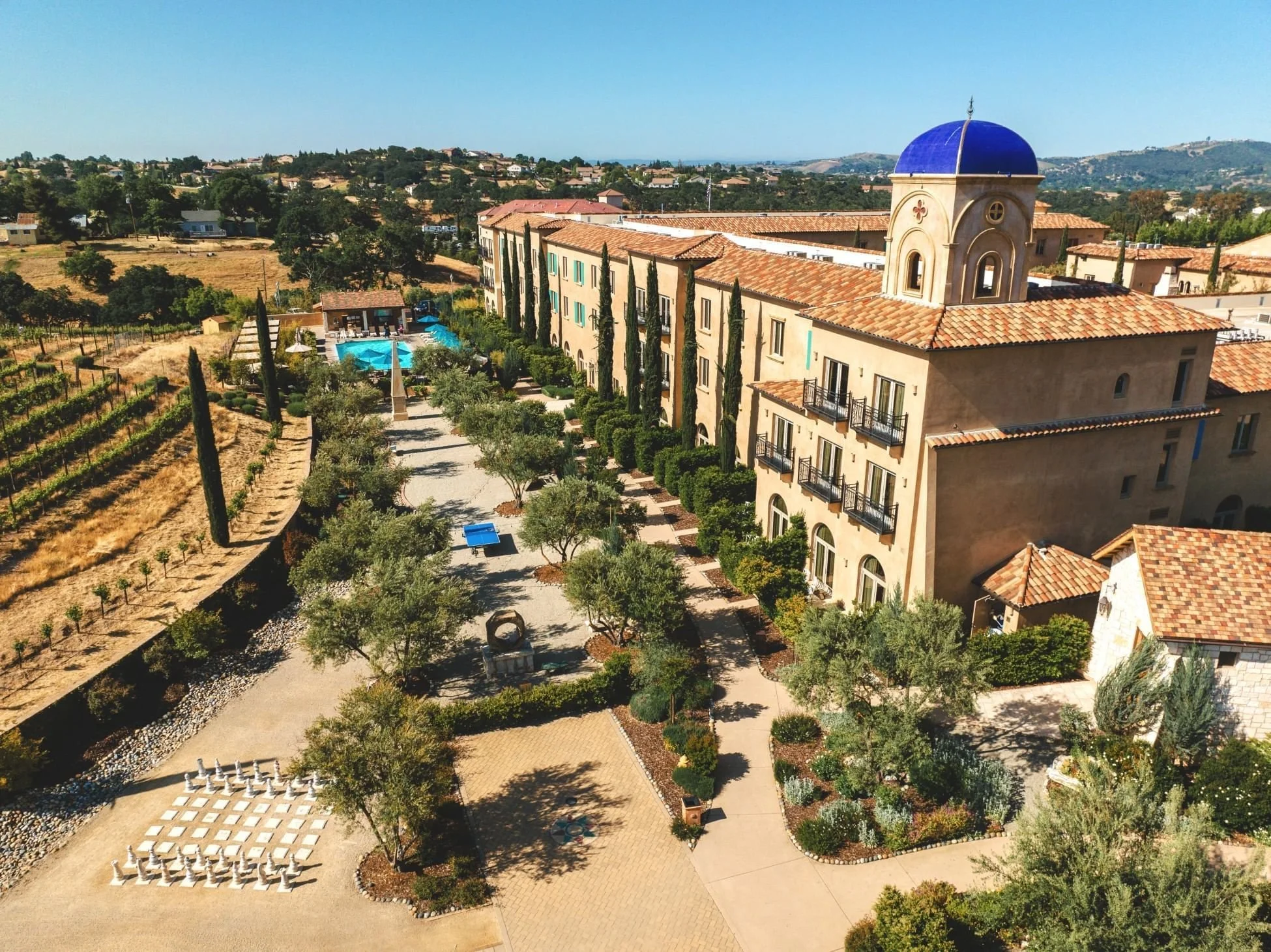 An aerial photo fo Allegretto Vineyard Resort, surrounded by hills, walking paths, and a pool.