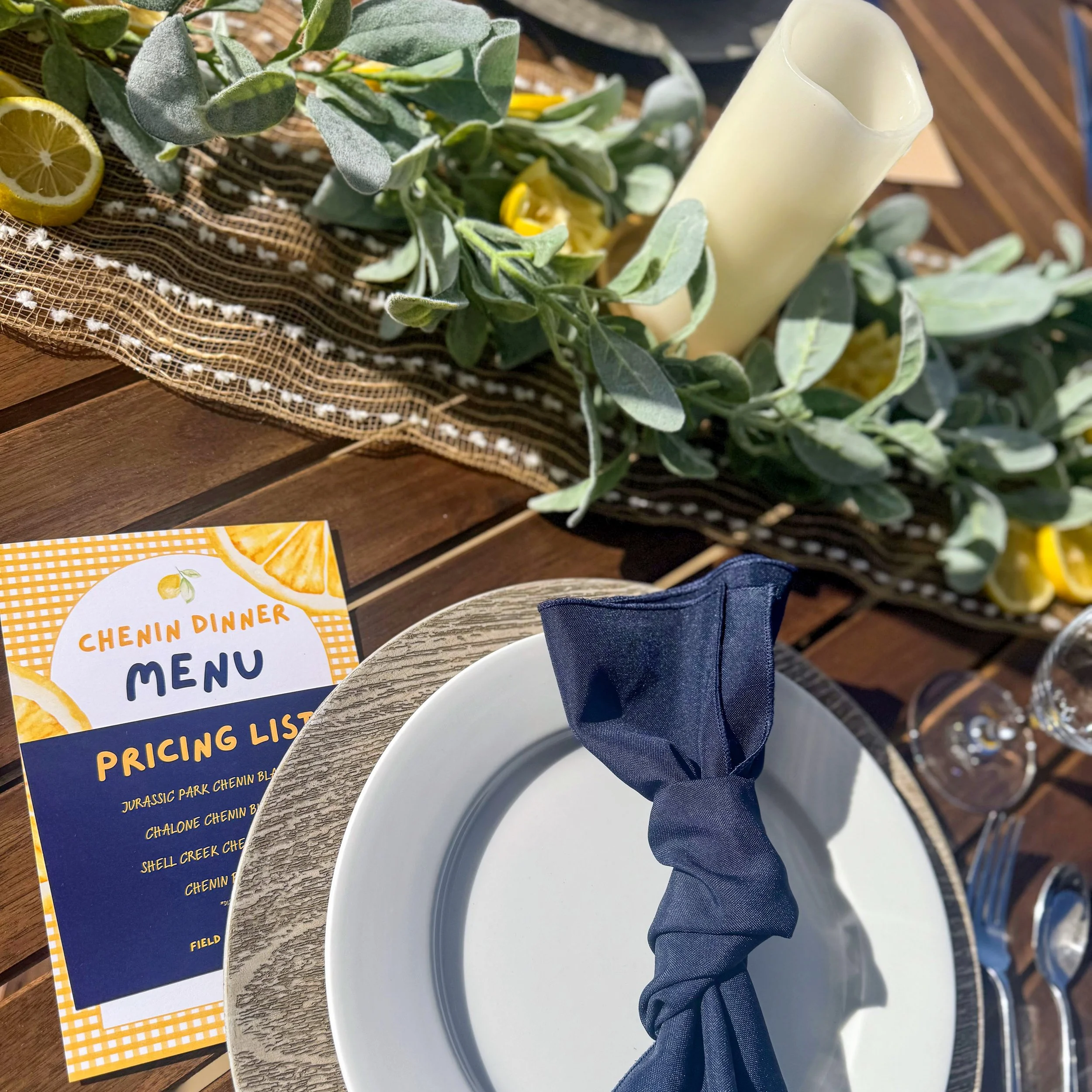 A table setting with a lush green table runner design, with a bright yellow menu to the side.