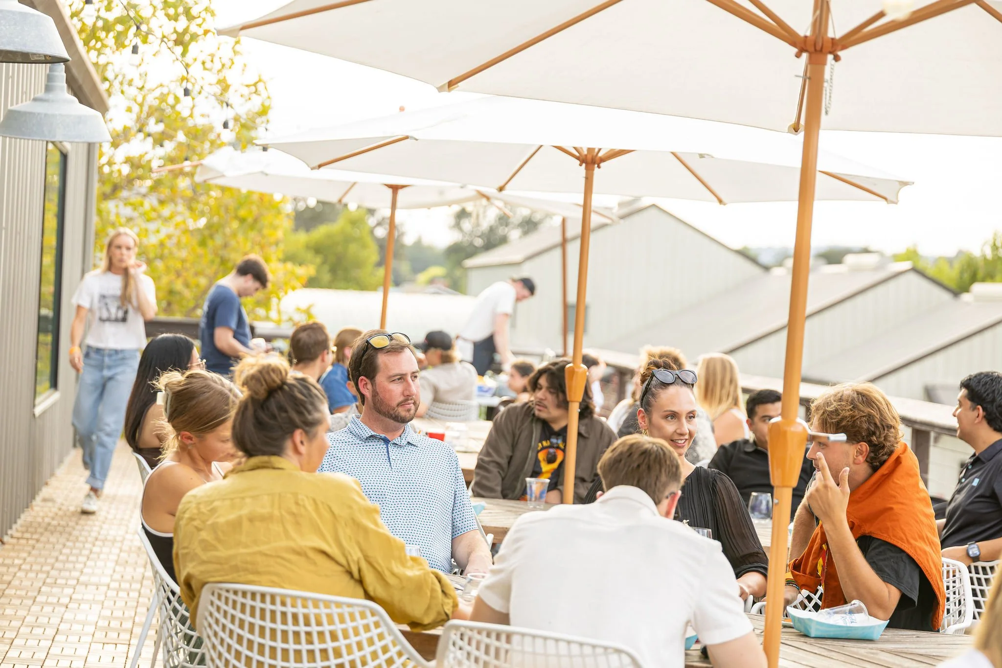People enjoying an outdoor gathering with umbrellas and tables on a patio