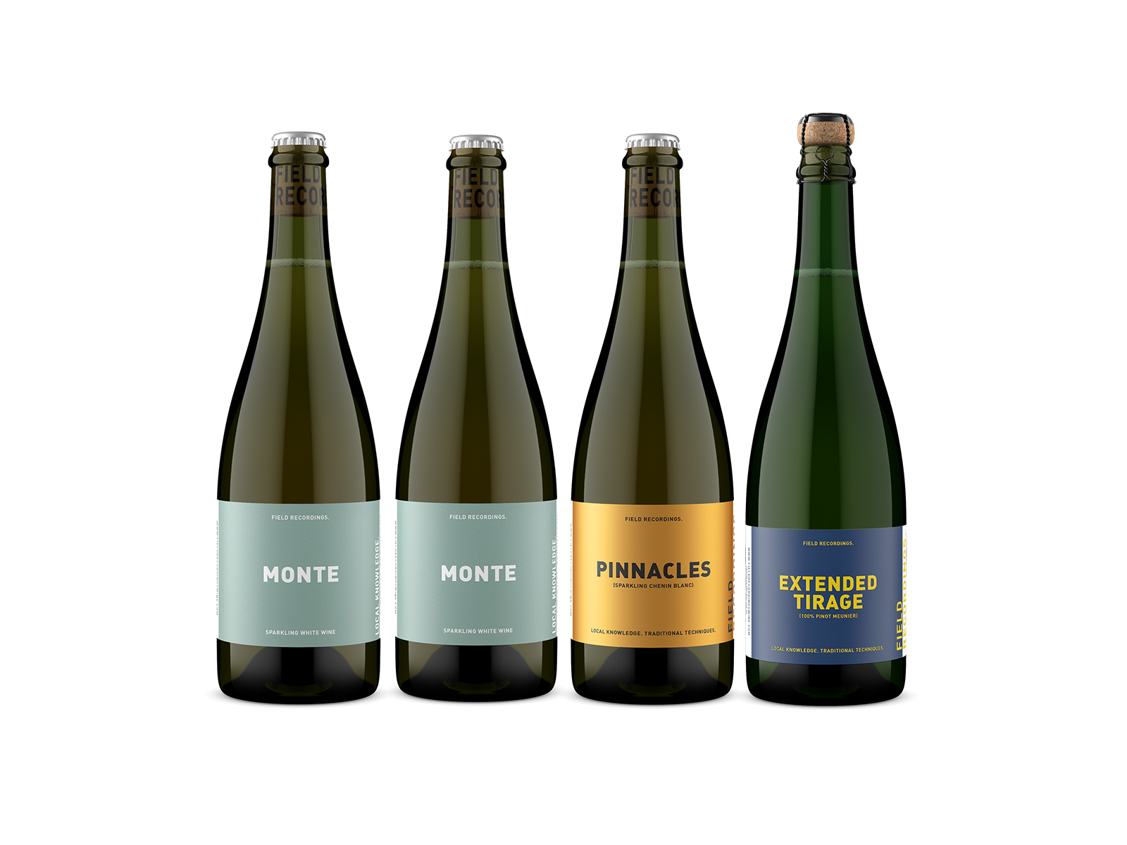 Four bottles of wine in a row. Two are Monte, with a light seafoam label and white text. One is Pinnacles, with a shimmery gold label. The final bottle is Extended Tirage, with blue label and yellow text.