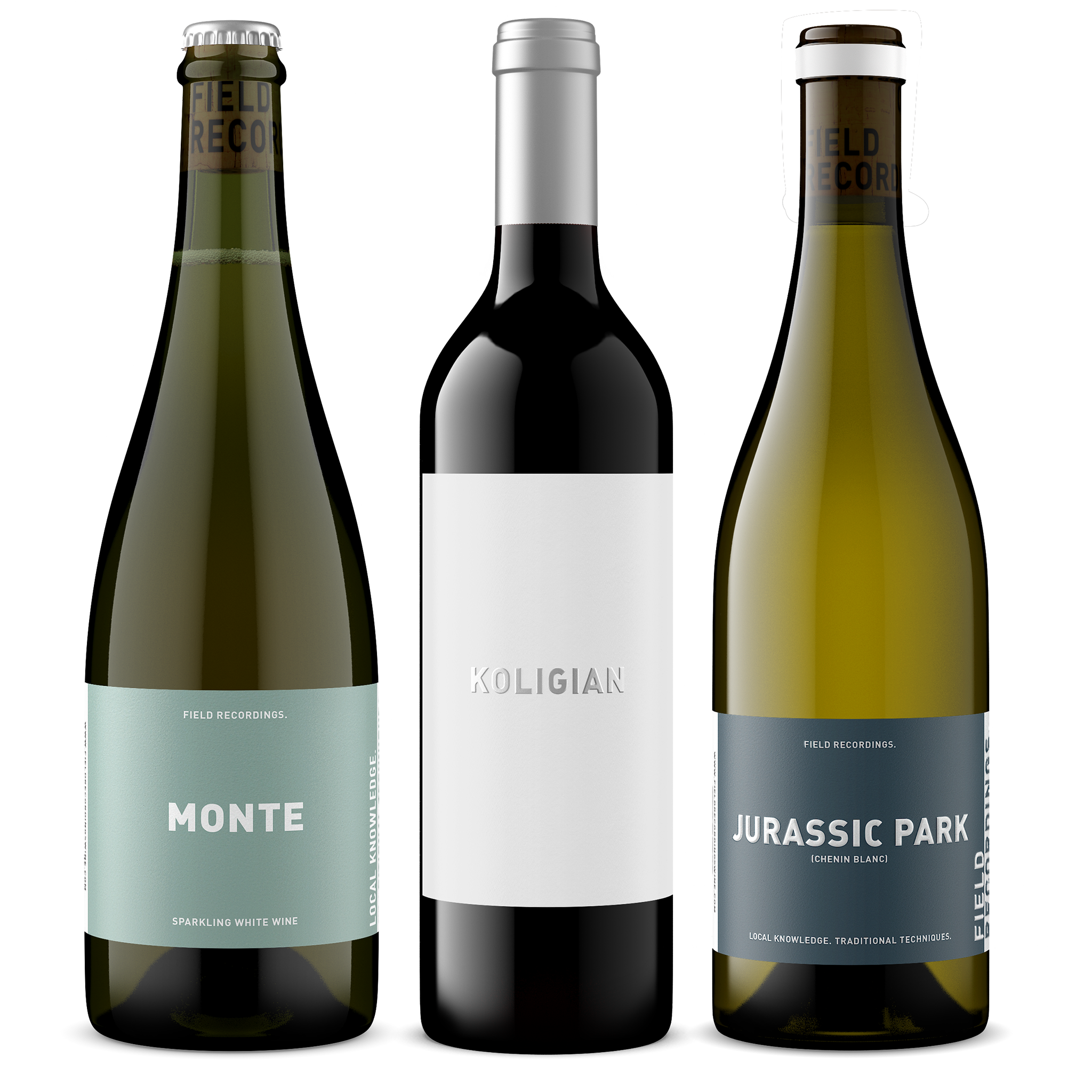 Three bottles of wine arranged in a row. From left to right: Jurassic Park Chenin, green glass with a blue label; Koligian red field blend, with black glass and a white label; Pinnacles sparkling Chenin Blanc, with green glass and a gold label.