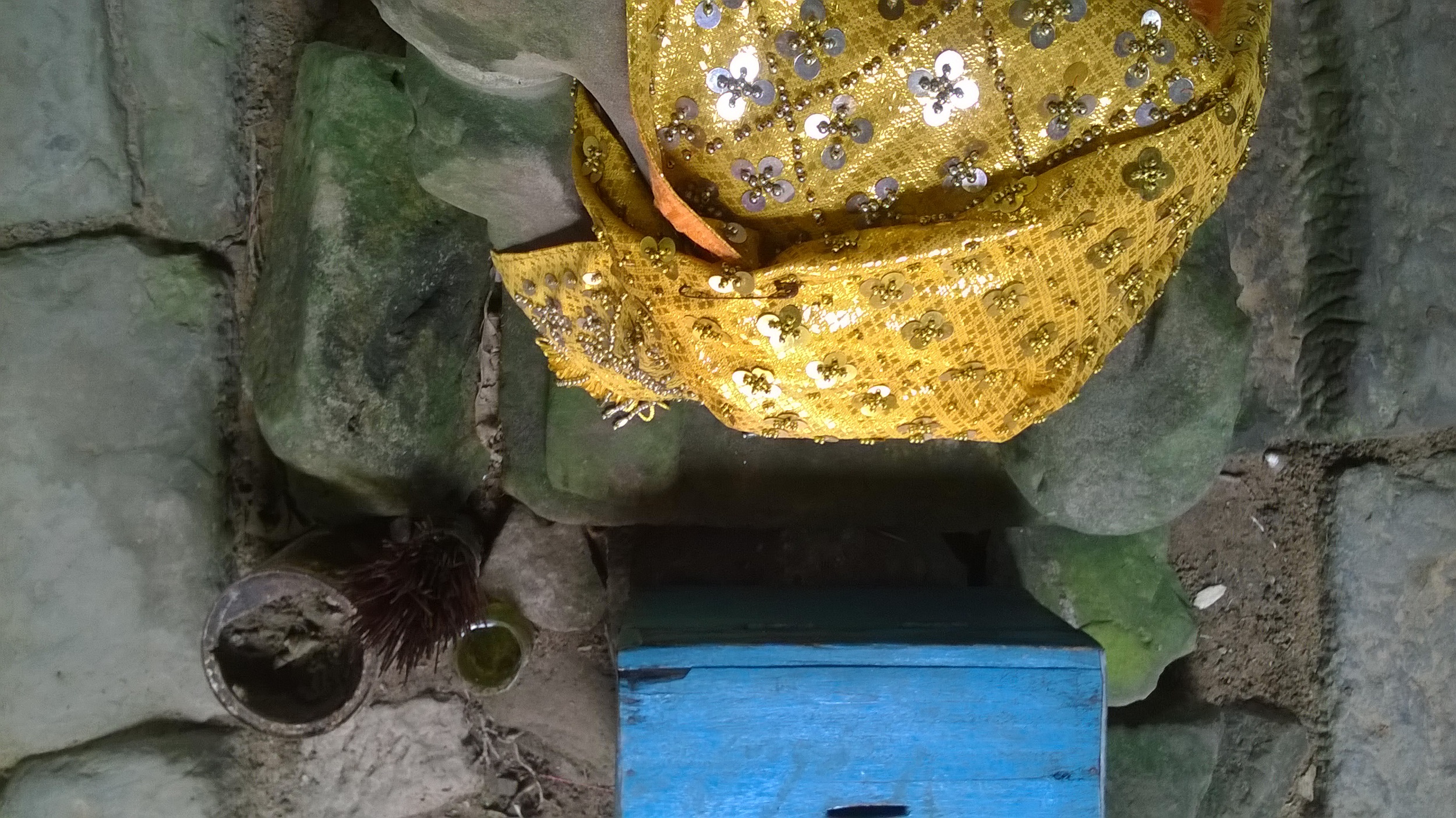 A headless Buddha with worn feet and a donation box in an ancient temple near Siem Reap, taken from above.