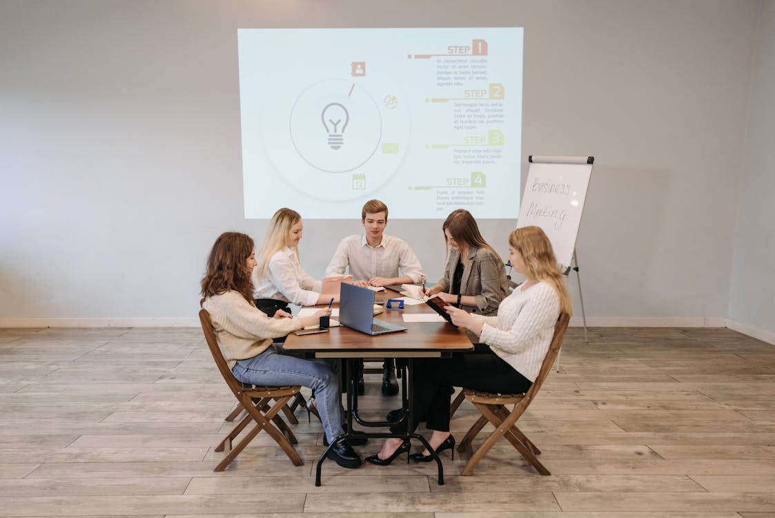 A professional rehearsal session for a virtual event with presenters reviewing slides on a laptop