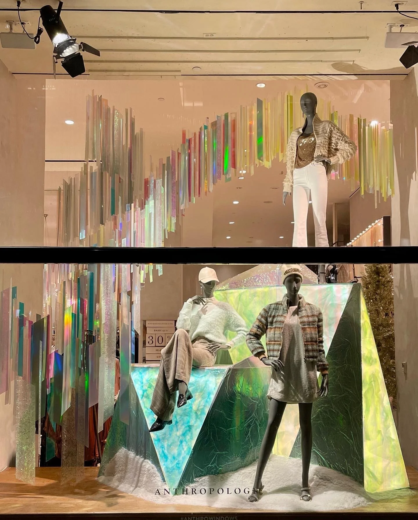 Store window display with mannequins dressed in fashionable outfits and colorful, iridescent decor.