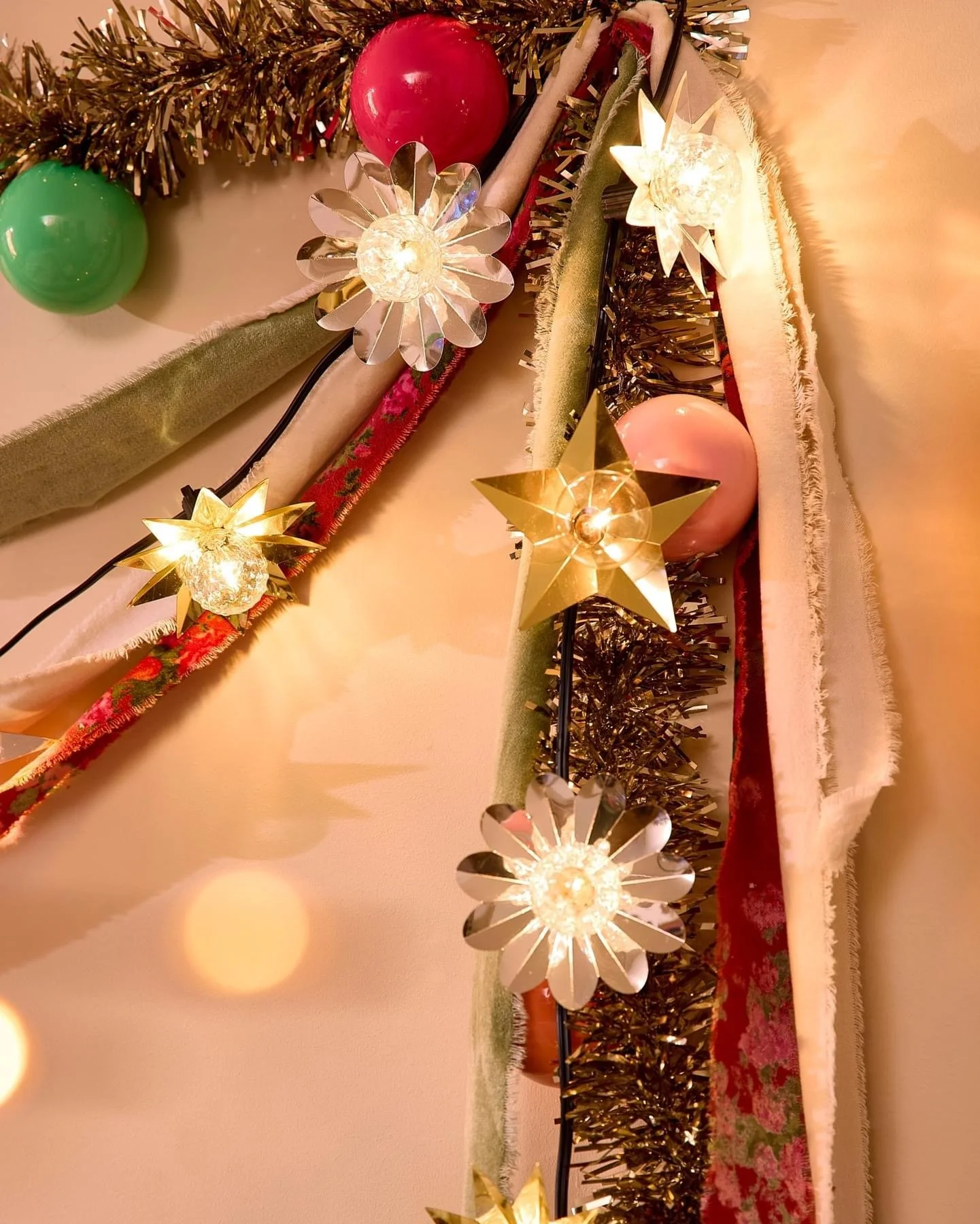 Close-up of Christmas decorations including string lights with star and flower designs, tinsel, ornaments, and fabric garlands.