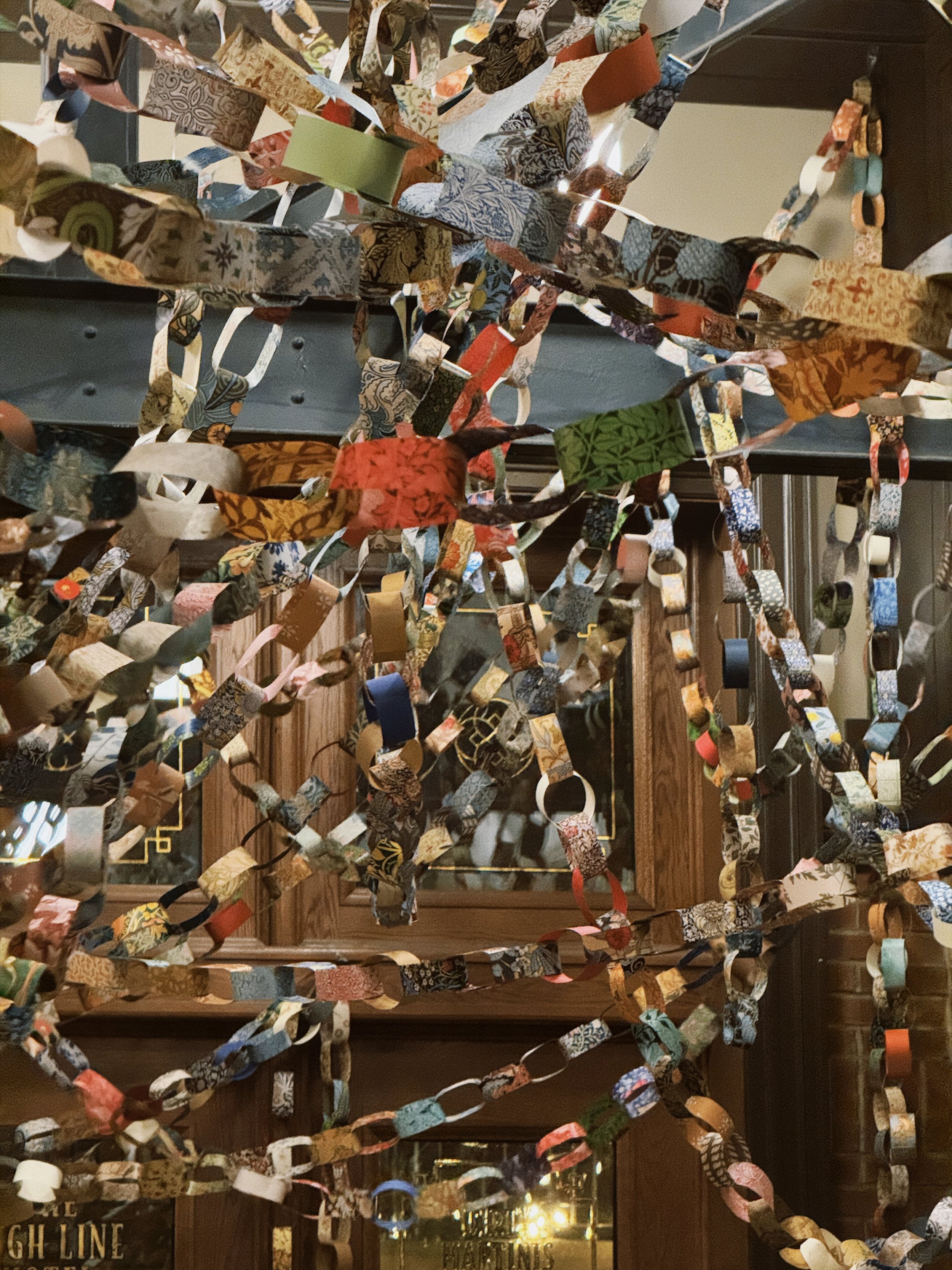 Colorful paper chains hanging from the ceiling in a room with wood-paneled walls and mirrors.