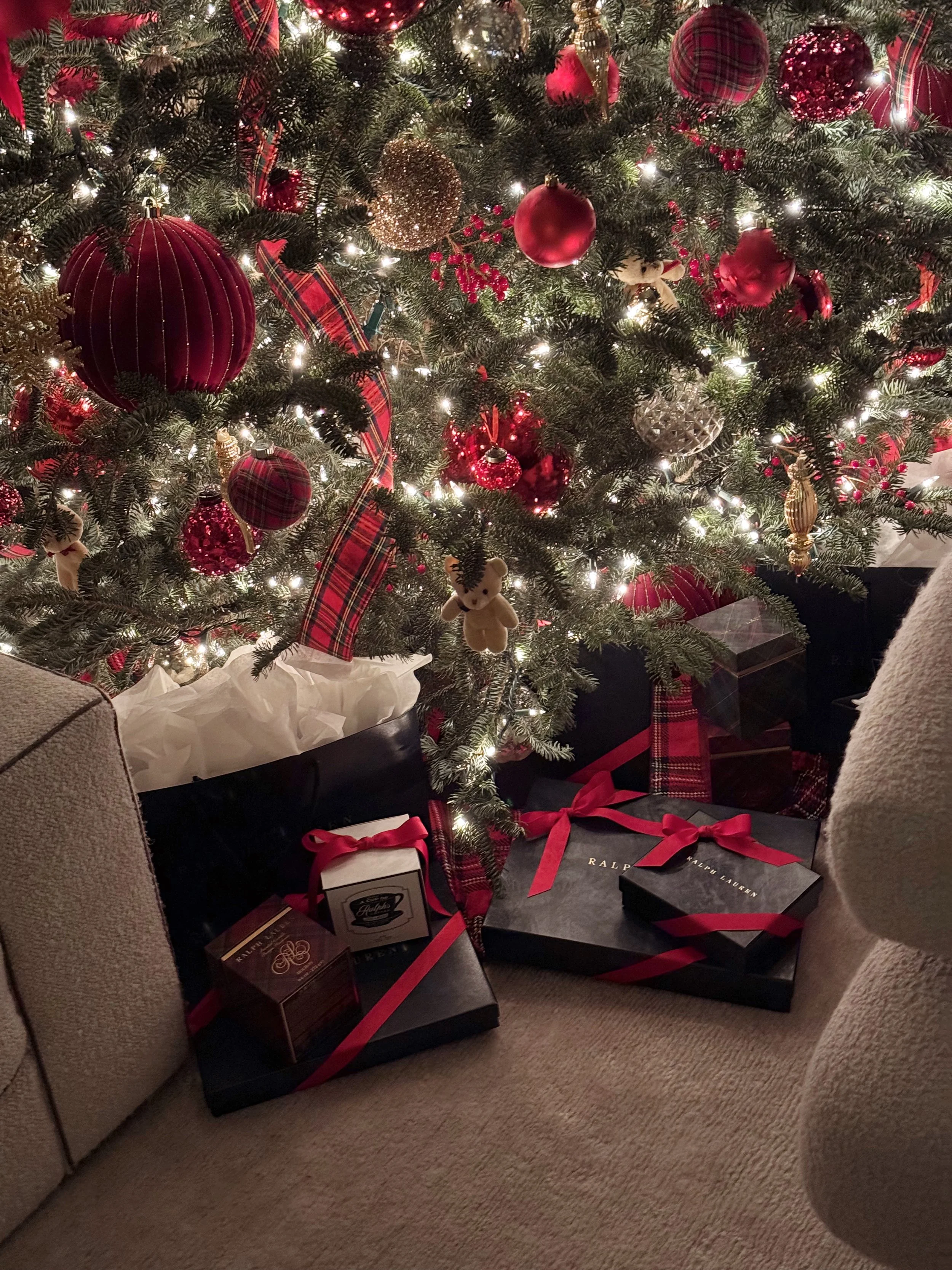 Decorated Christmas tree with red and gold ornaments, candy canes, plaid ribbons, teddy bear ornaments, and white lights, with wrapped gifts underneath.