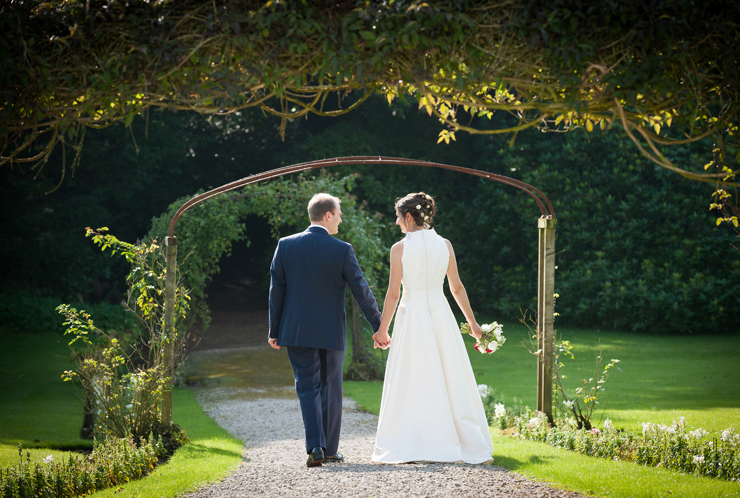 Bride & Groom walking through the gardens at Leighton Hall