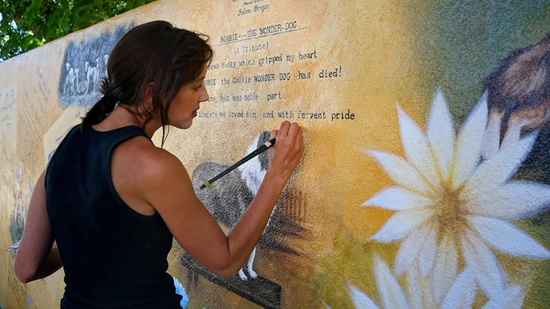 Although not one of the original artists, Lissa Jensen retouches blemishes on Silverton Bobbie's Memorial Mural on Water Street in downtown. Photo by Stewart Harvey