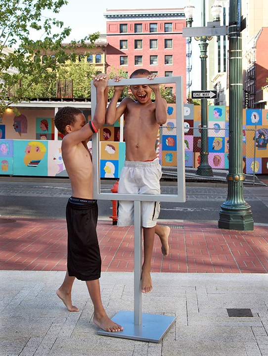 Young boys play on an empty sign holder at Director Park in downtown Portland. Photo by Cathy Cheney