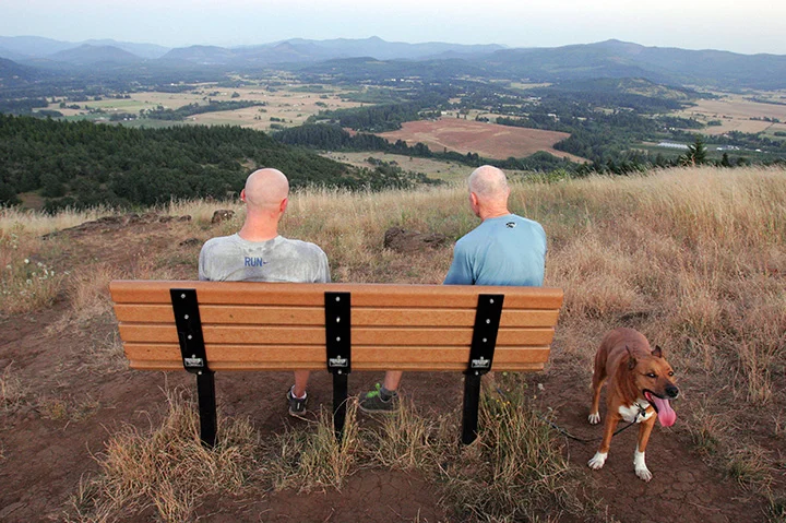 Andrew Dow (left) and his father, Doug, (and Jack the dog) enjoy the view from Mount Pisgah shortly after sunset. The hill, rising about a thousand feet above the surrounding area, is a popular hiking spot, offering panoramic views of the southern Willamette Valley. Photo by Rob Romig