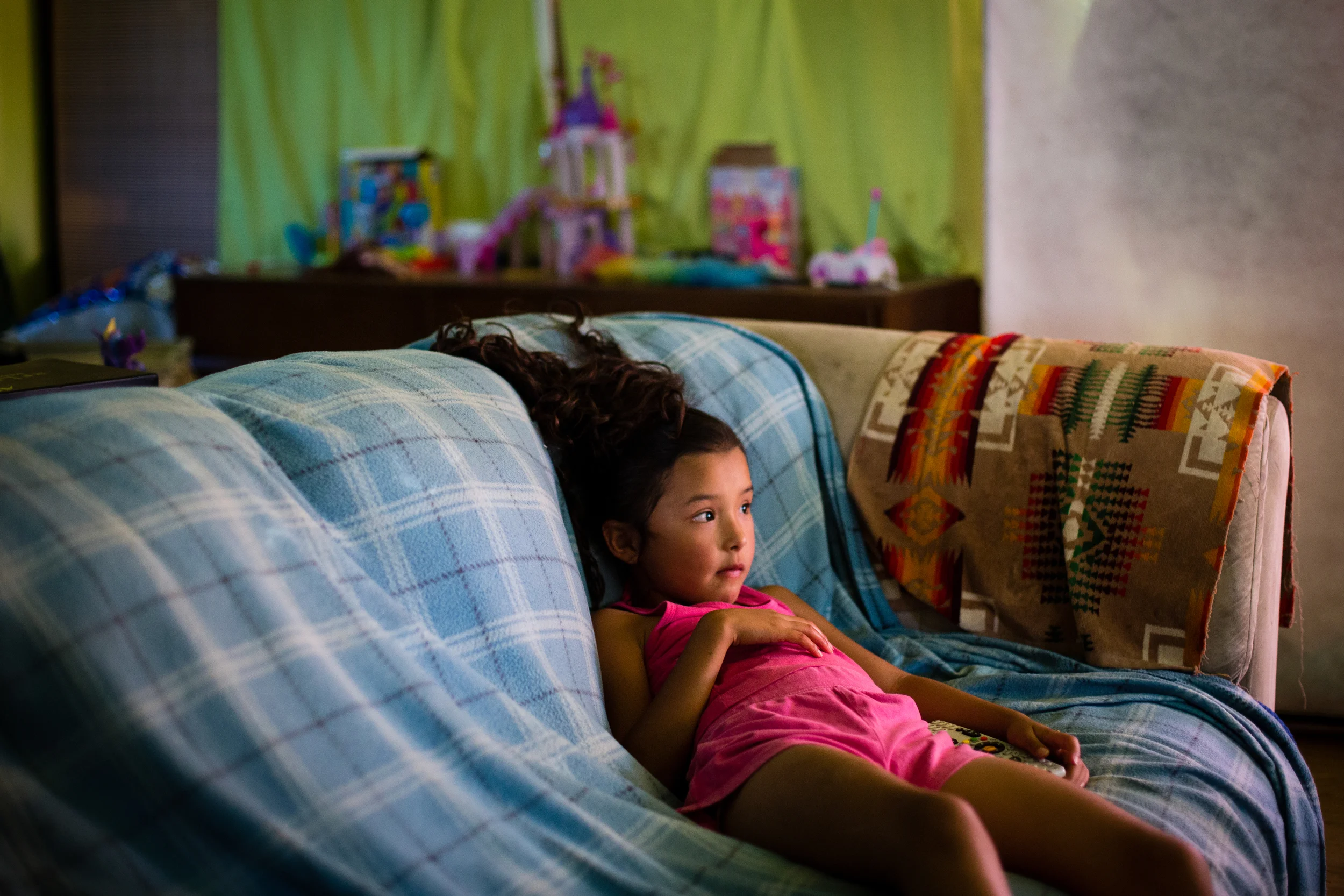 On Monday, July 15, 2013 Kahmussa Green, 7, watches cartoons at her home in Warm Springs, OR. Adopted by her mother, Charlie Green, her name means respect. Born to an addicted mother, this lover of ballet spent the first days of her life going through withdrawl. Her adopted grandmother Lucinda's household numbers 11 total and includes her husband Sterling, a former rodeo cowboy, their son Casey and daughter Charlie, their spouses and children and a few they have adopted along the way. The family has 188 acres with the Deschutes River bordering one side, but only 37 of it is flat which they use for gardening and breaking horses.