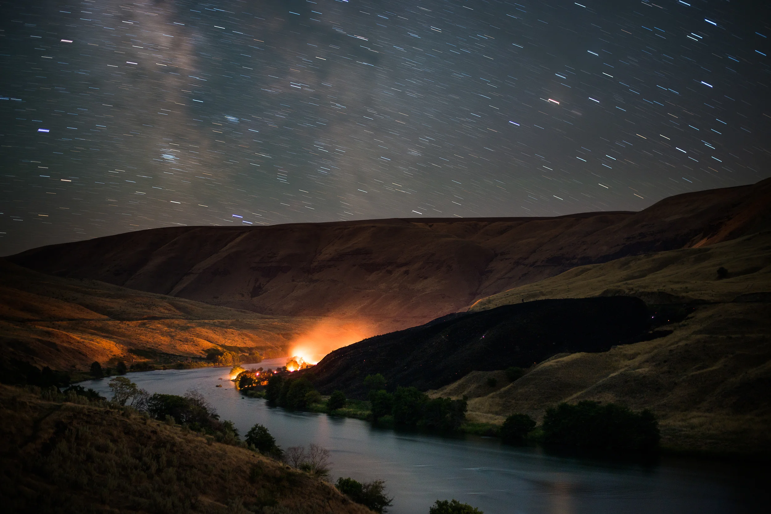 12:23am, July 15, 2013
The glow of a mostly extinguished brush fire on the Lower Deschutes River about 2 miles upstream from where the Deschutes meets the Columbia lights up the canyon walls in this 2 1/2 minute exposure well after fire crews contained the blaze and left the scene.