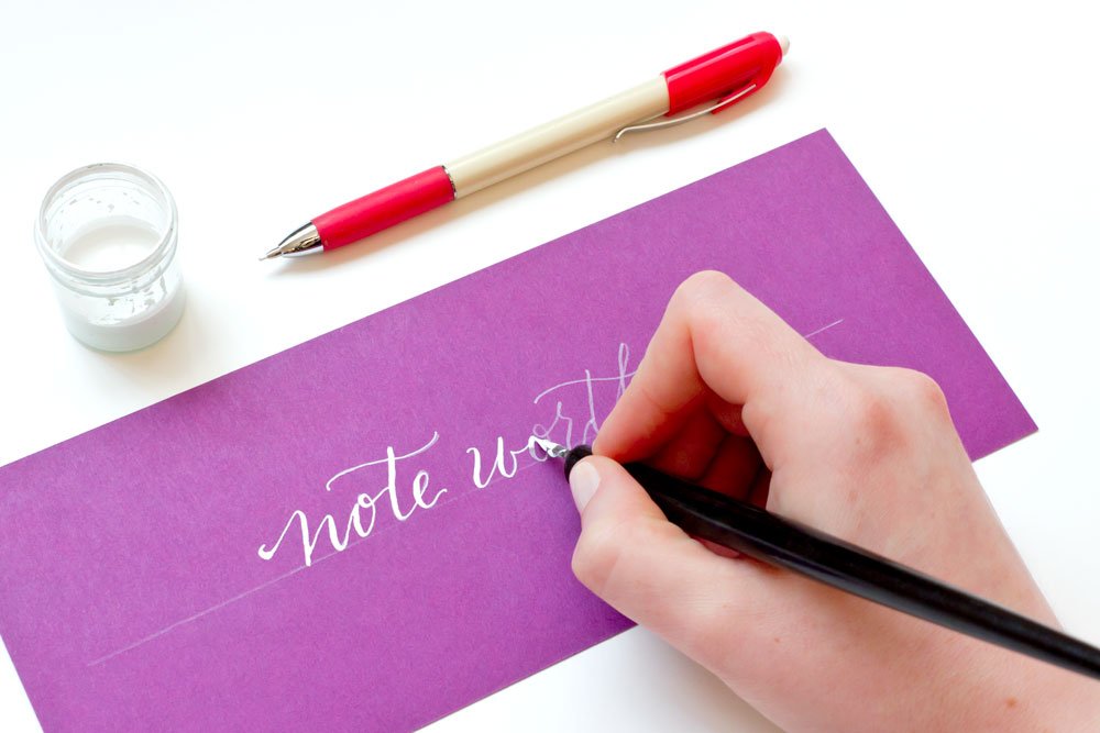 Demonstration of calligraphy technique using white ink on purple paper