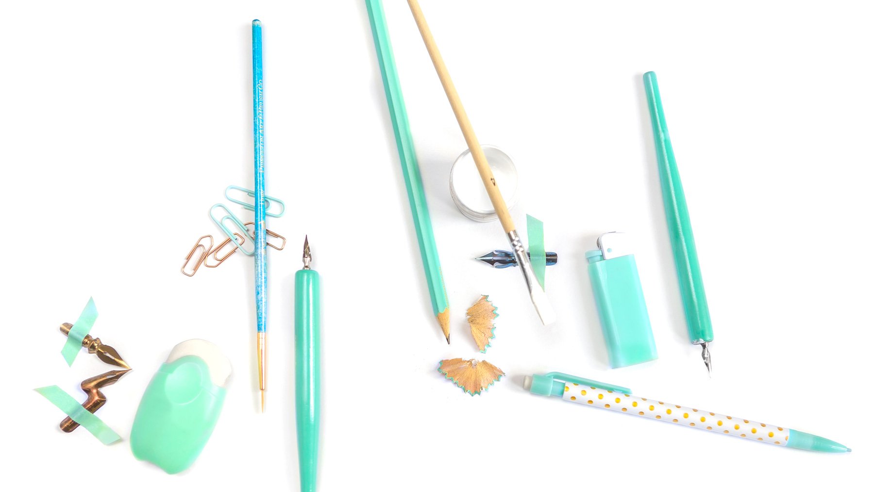 An array of turquoise writing supplies like calligraphy pens, pencils, nibs, and brushes