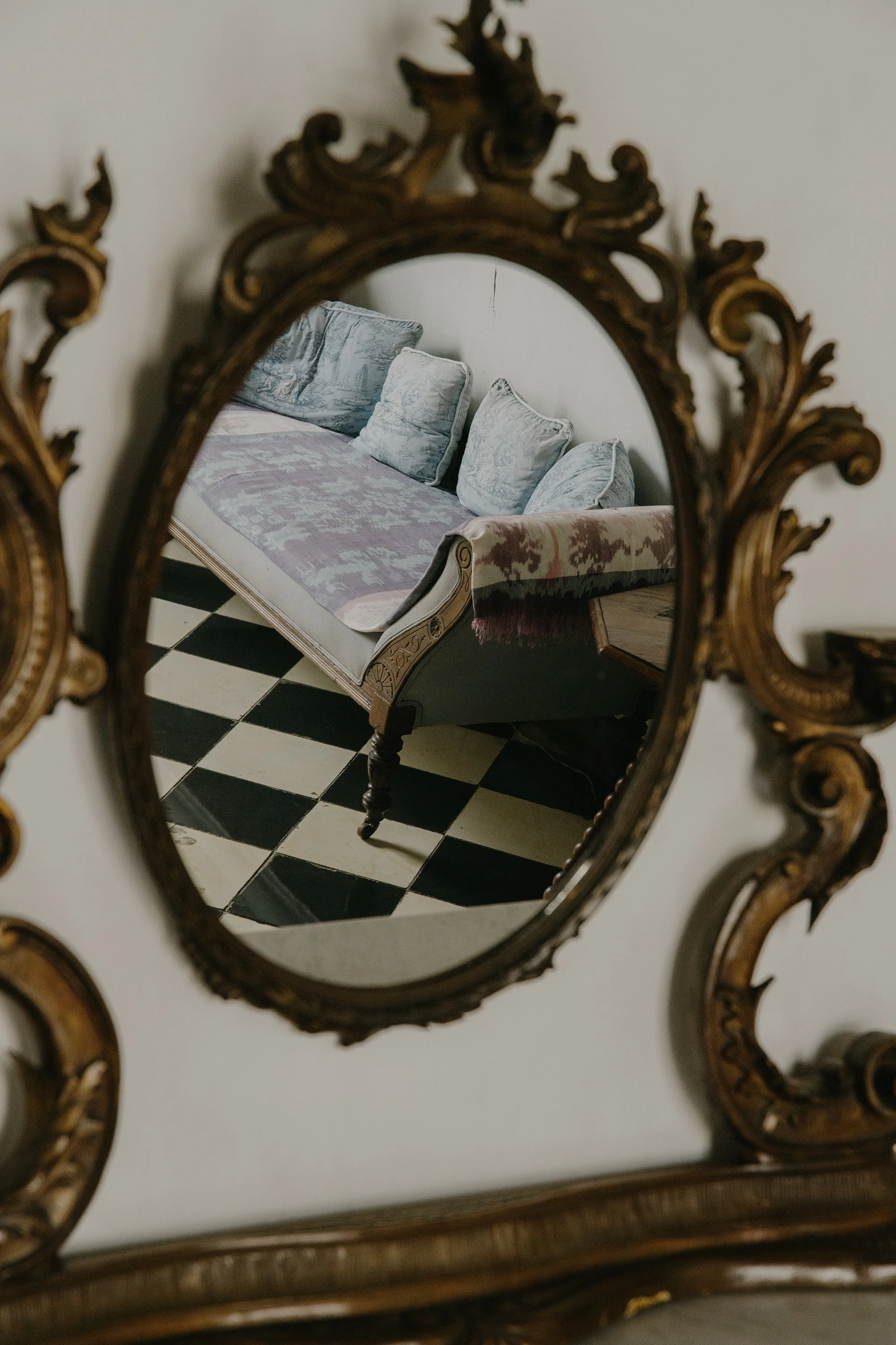 An ornate there representing a sofa and a wall mirror with a black and white checkered floor. Mundos Interiores. Ciudad Colonial de Santo Domingo.