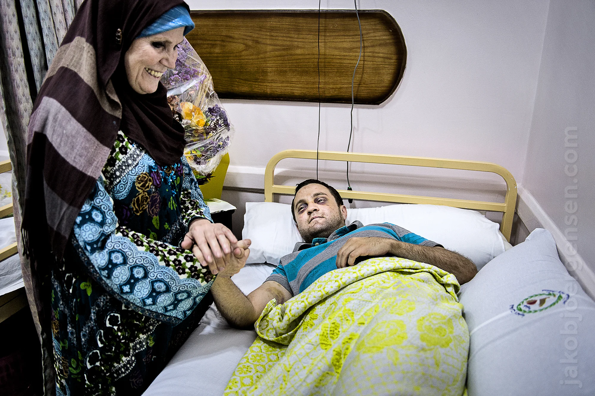 Karim gets a visit from his mother at the hospital. He was nearly killed when a crowd of pro-Mursi people attacked him on his way back from work as a policeman. They thought he was from the military. Karim was severely beaten and stabbed twice. July 2013.