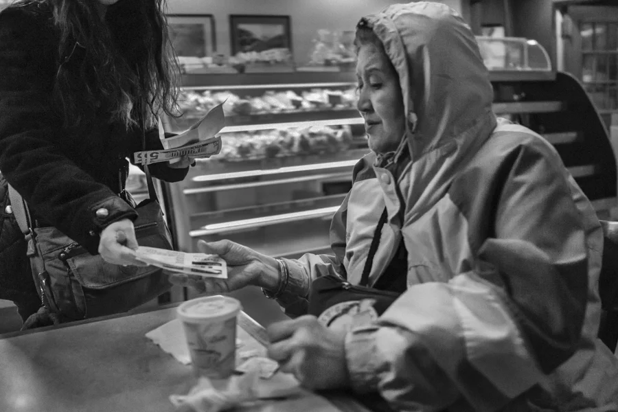 Yoyo, left, a Chinese tour guide of the 'Lucky 9 Enterprise' bus company sells bus tickets in a bakery store at Flushing, Queens, United States, Mar. 6, 2013.