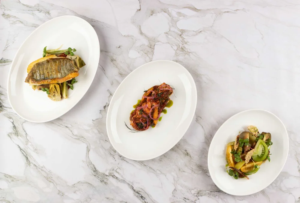 Three white oval Elia plates with plated dishes