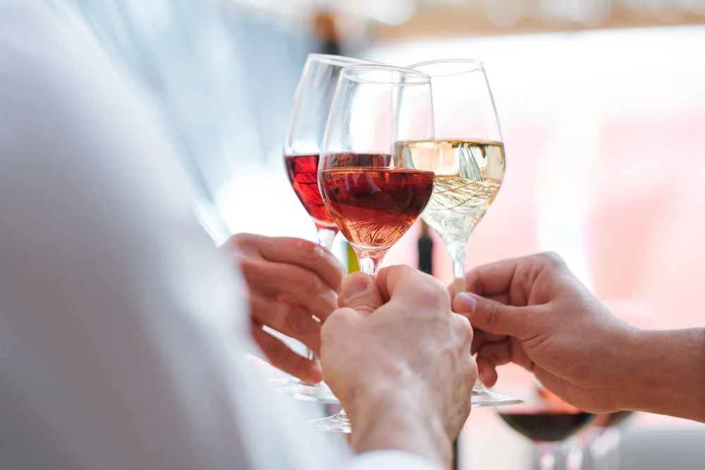 Glasses of red and white wine raised in a toast
