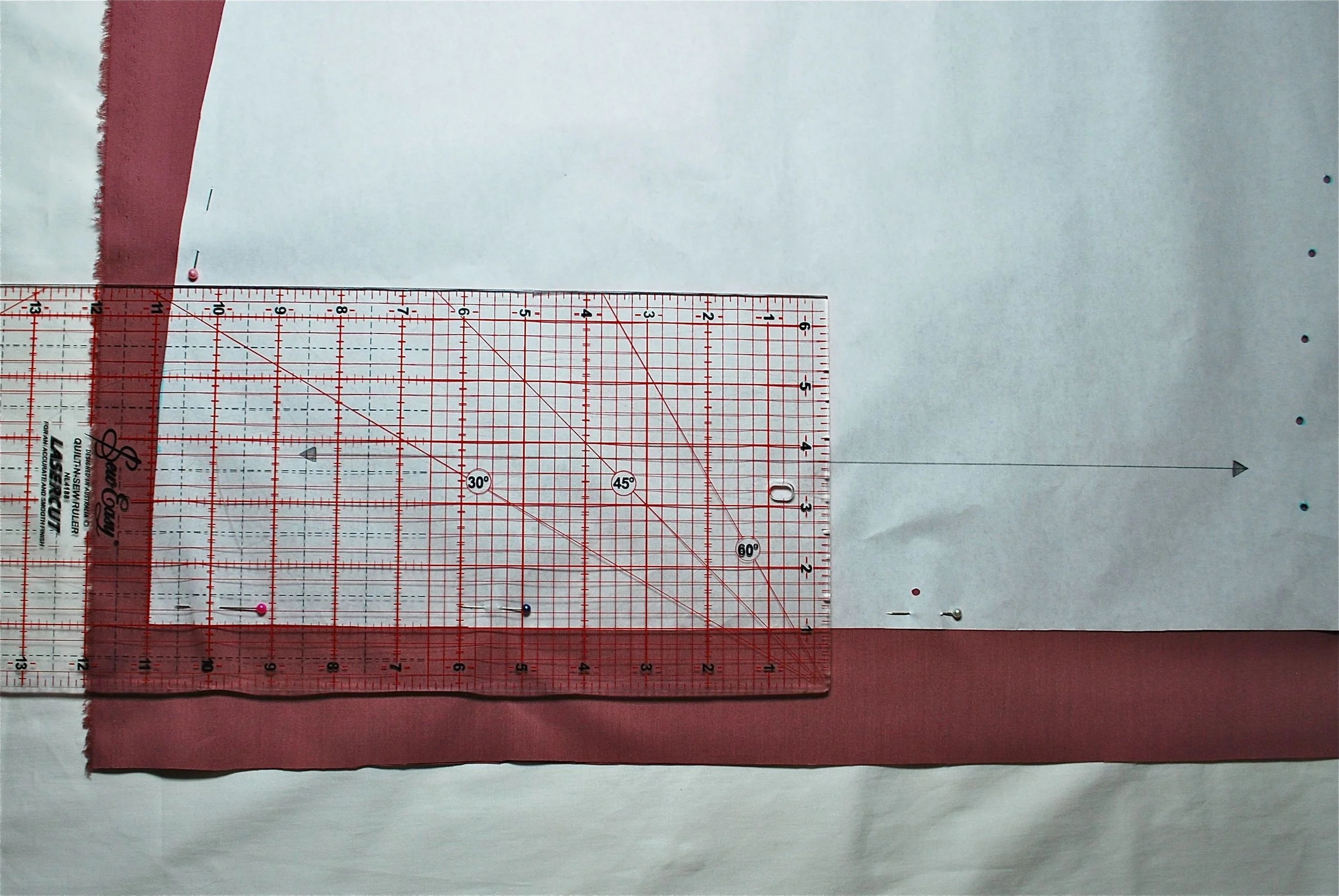 See above how the straight line of the grain line arrow is positioned parallel to the lines on the quilting ruler.