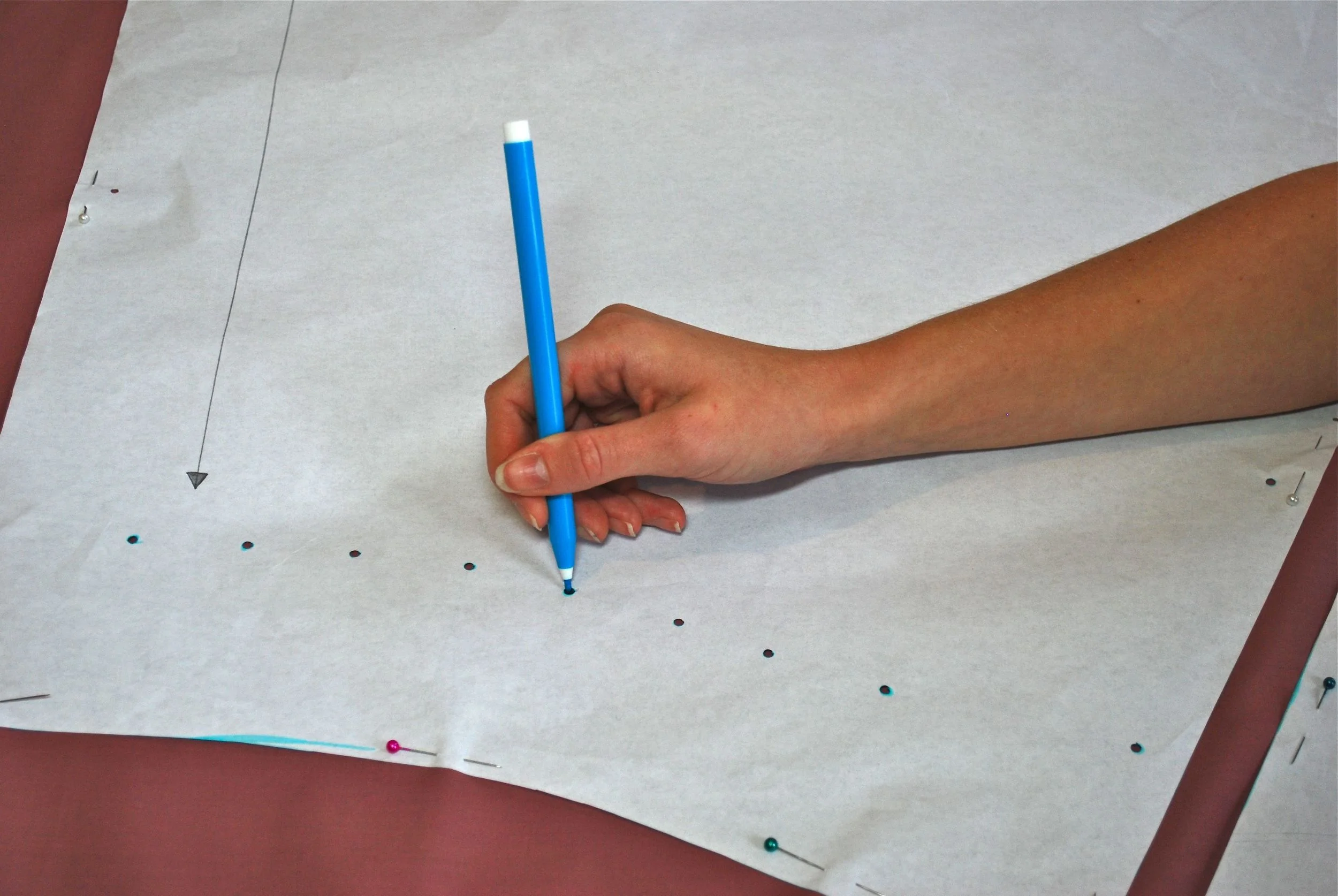 Marking out pleats on Naomi's pattern pieces. We punched holes thorough the small circles that were on the pattern, then stuck our pen through the holes to mark the fabric.
