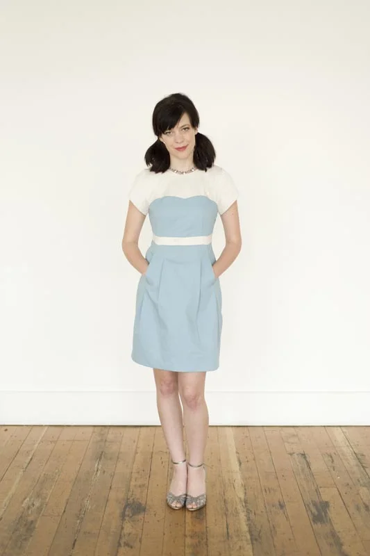 MACARON Colette A flattering and curvy dress. Includes a bodice fitted with darts, along with a contrasting top yoke, sleeves, and narrow midriff band. Short sleeves are gently scalloped along the sleeve hem, echoing the shape of the bodice. Skirt has large pleats, with pockets hidden in the front pleats. Closes with an invisible side zipper. 