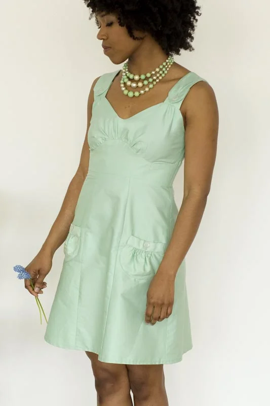 PARFAIT Colette A versatile dress designed to be worn as either a sun dress or layered over a shirt or blouse as a pinafore style in cooler weather. Features a gathered bust and flattering curved midriff that fits snugly around the high waist. The straps and gathered pockets fasten with buttons. Skirt is a gently flared six-gore style. Closes with a side invisible zipper. 