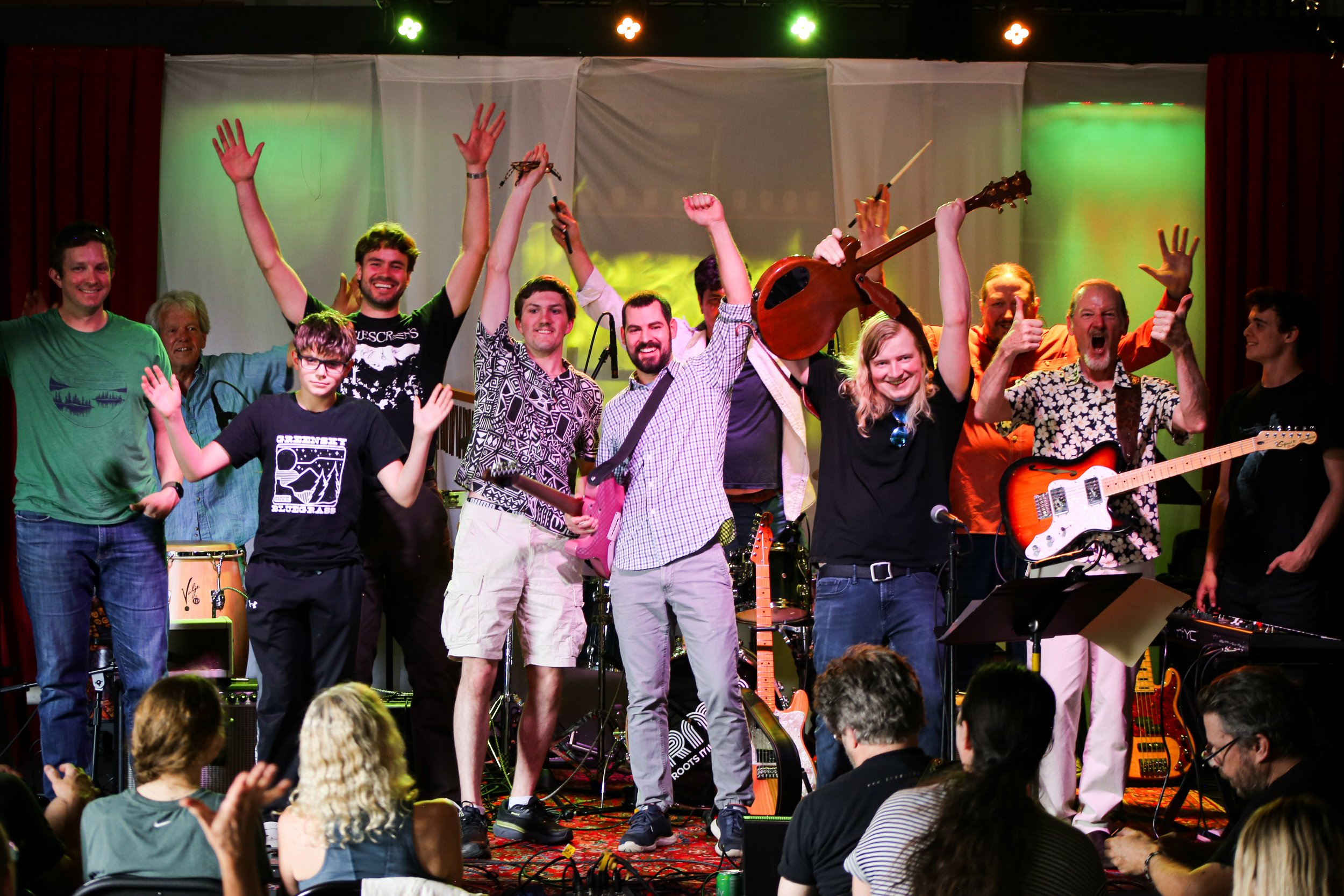 Group of people on stage at a concert holding musical instruments |  Boulder Guitar Coach | Wayne Daniels guitar coach