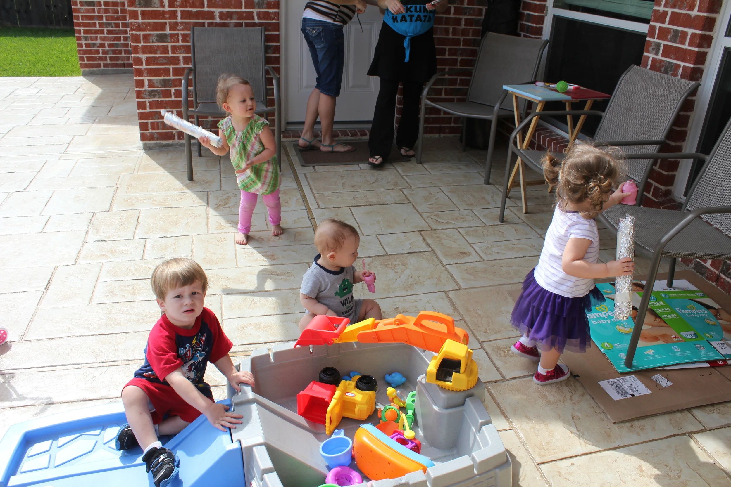 The mom-to-be's can just barely be discerned at the top of the photo, then we have Kenzie shaking her "rainstick", Avi swapping her rainstick for bubbles, Judah eating said bubbles lid, and Ben scaling the construction site wall. 