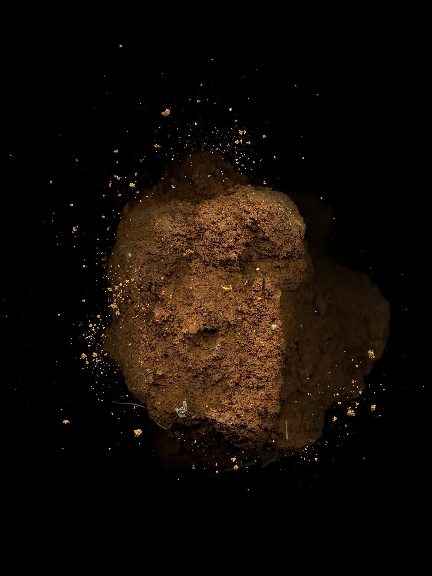 Clump of reddish brown dirt against black