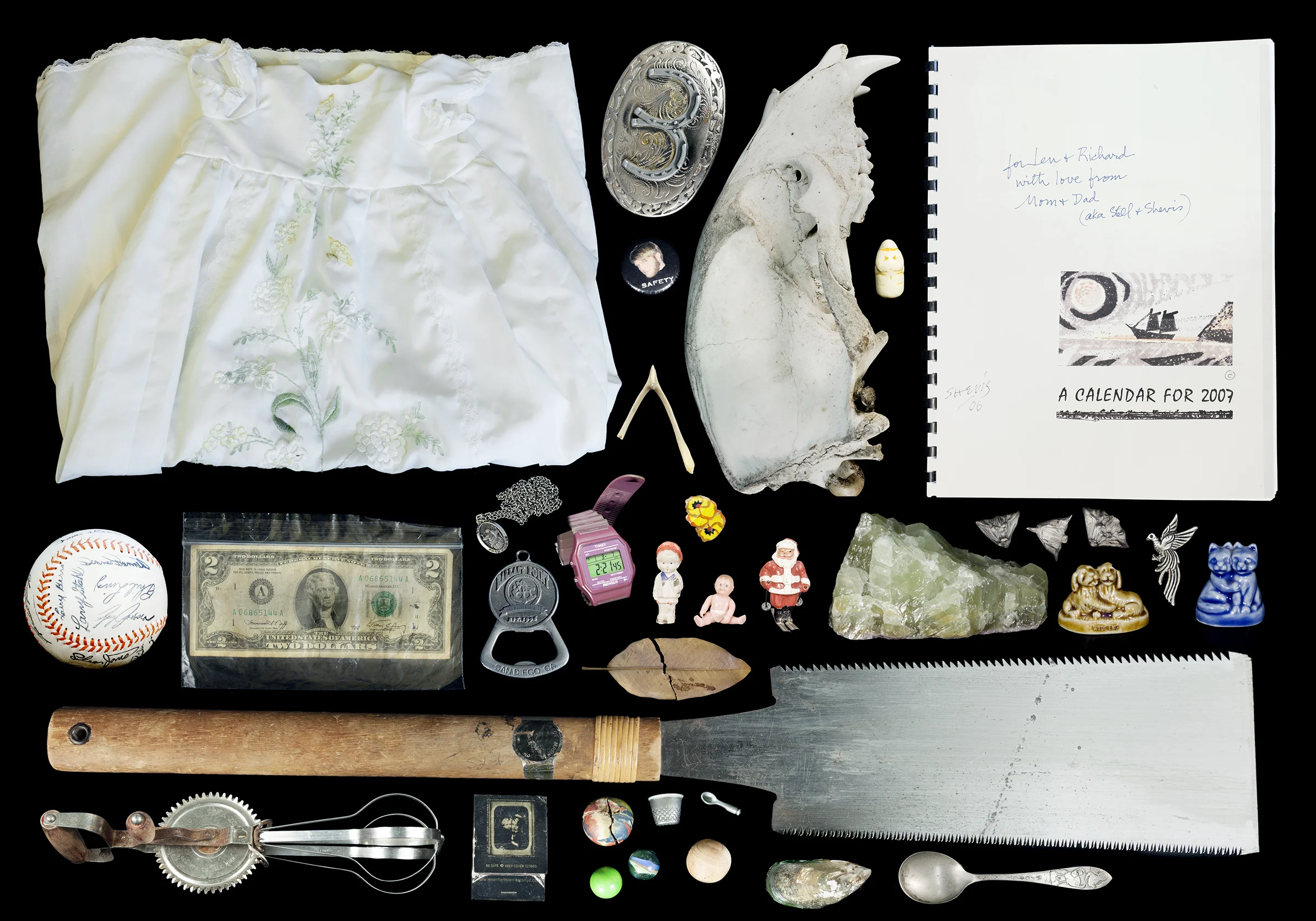 Collection of miscellaneous objects including a white embroidered cloth, large second place medal, two figurines, a baseball, dollar bill, watch, pink digital watch, a plastic statue, a large saw, a folding knife, a bunch of small figurines, a stone,