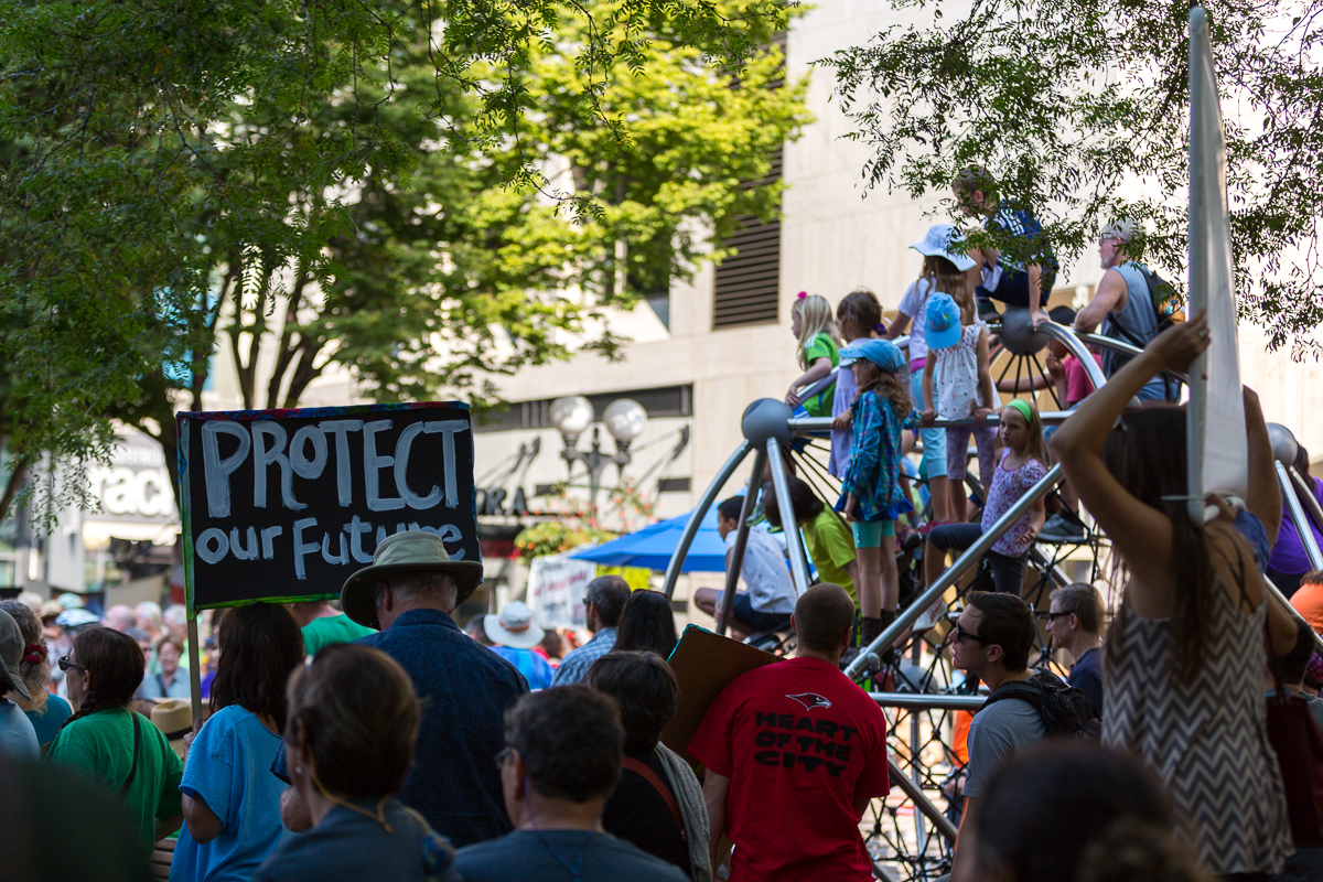 Adults listen to the speakers at a people's Climate rally in Seattle, WA. Meanwhile, children climb up high to get a view of the speaker and the crowd. September 21, 2014.