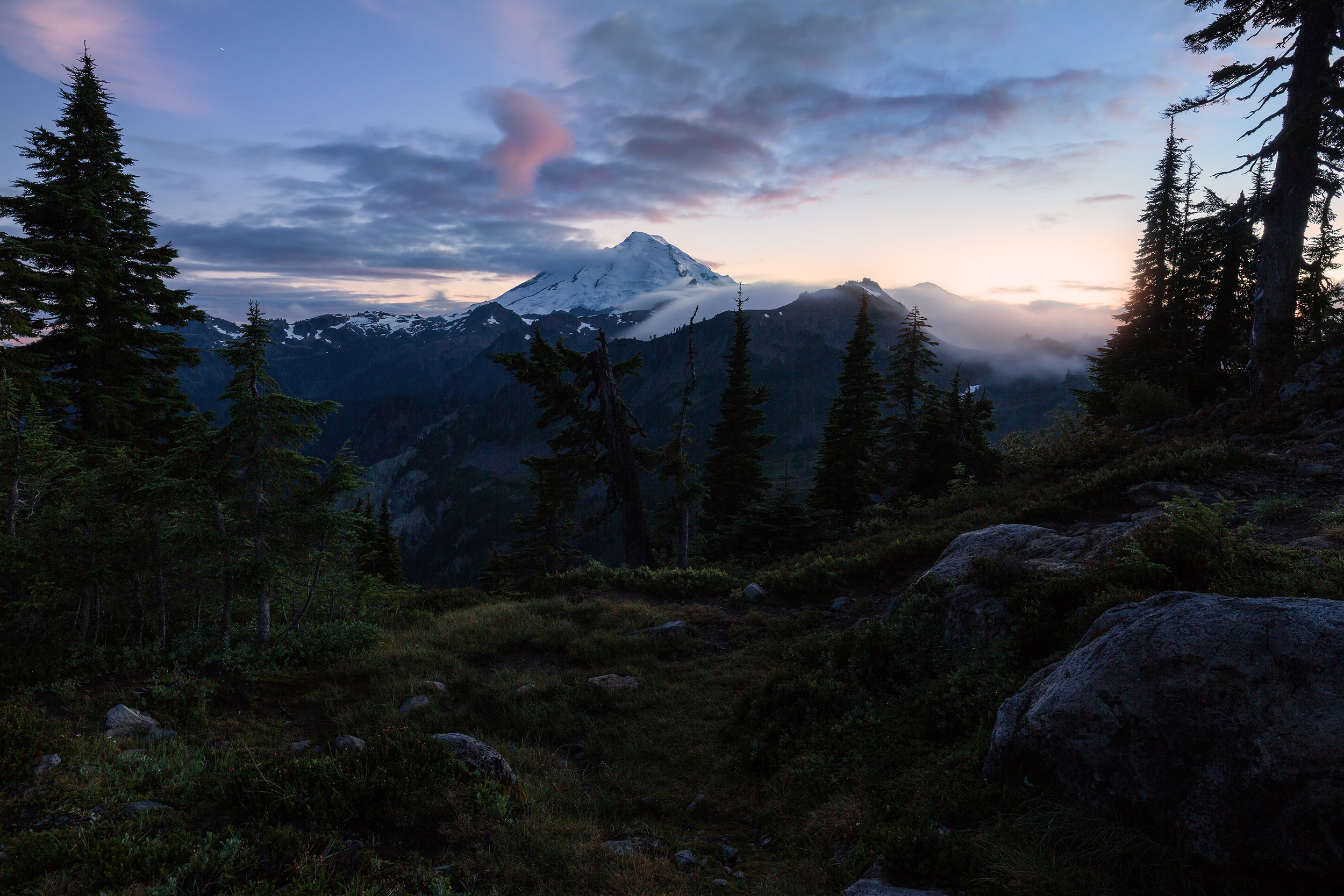  Mount Baker is consumed by twilight. The sun still illuminates the horizon in the distance. 