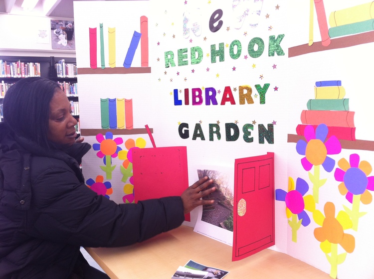 Sheryl Braxton works on the Participatory Budgeting Expo display for the Red Hook Library Garden project. See video .