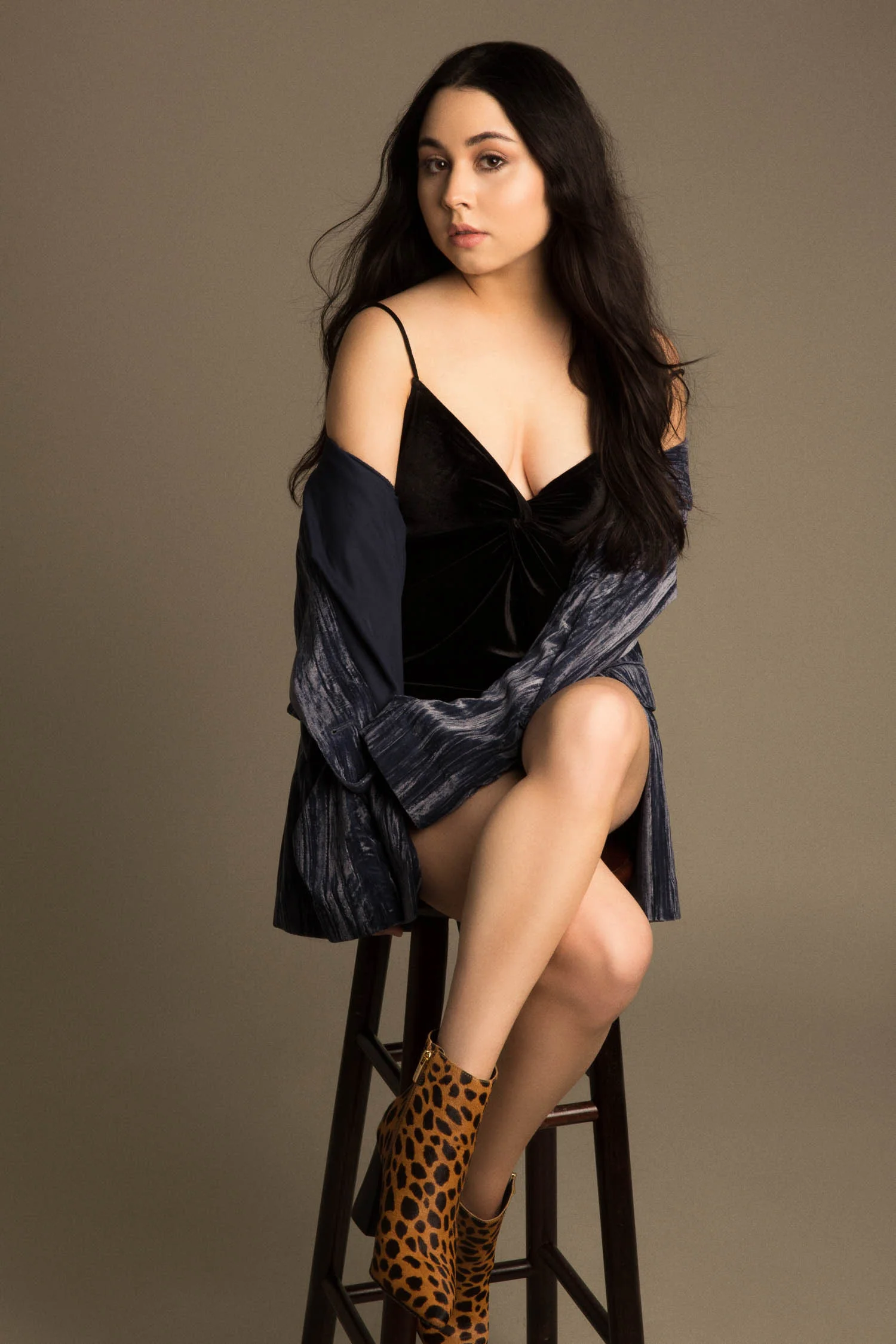 Model in velvet jacket sitting on a stool