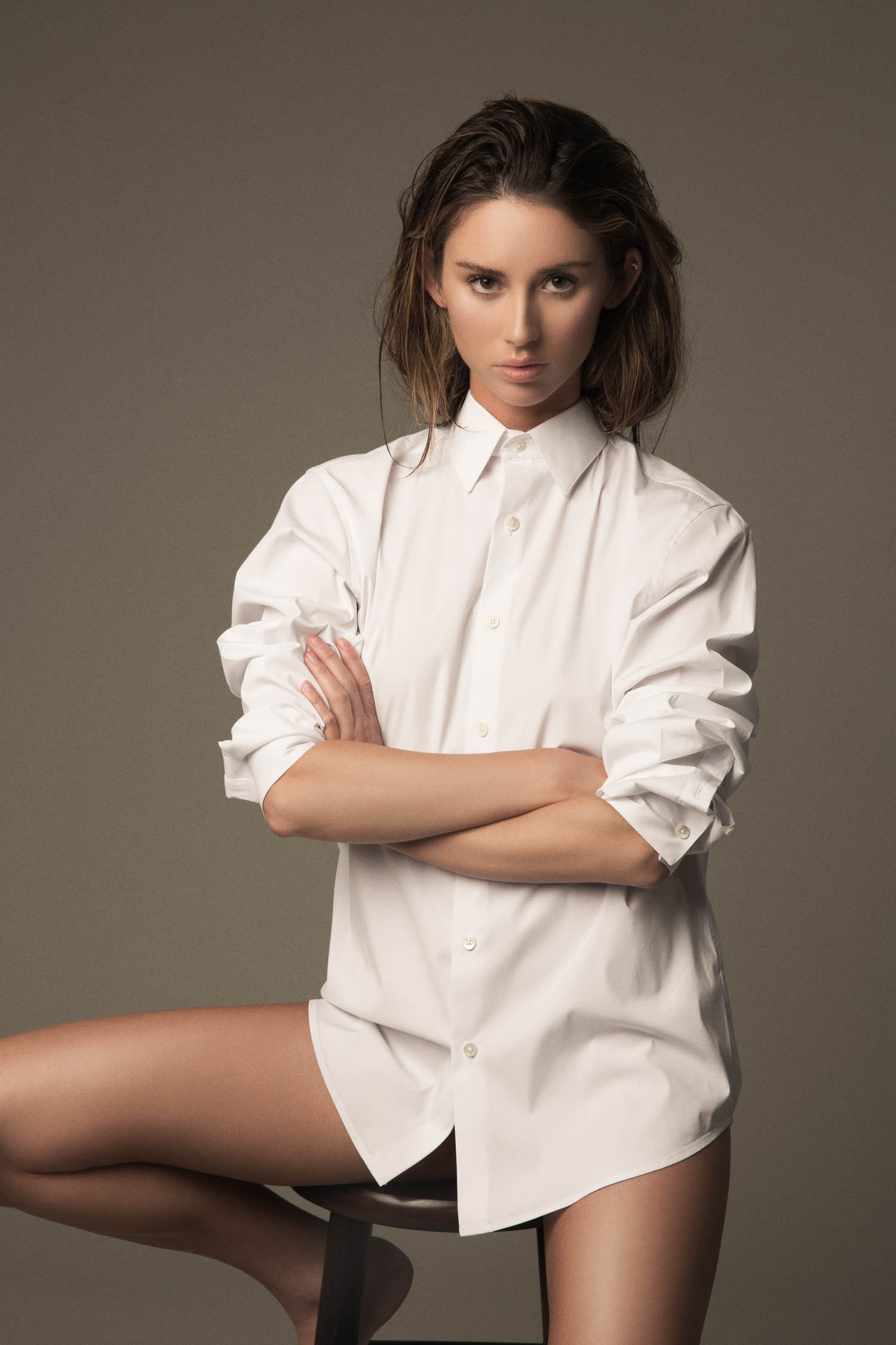 Model sitting in a white dress shirt with wet hair.