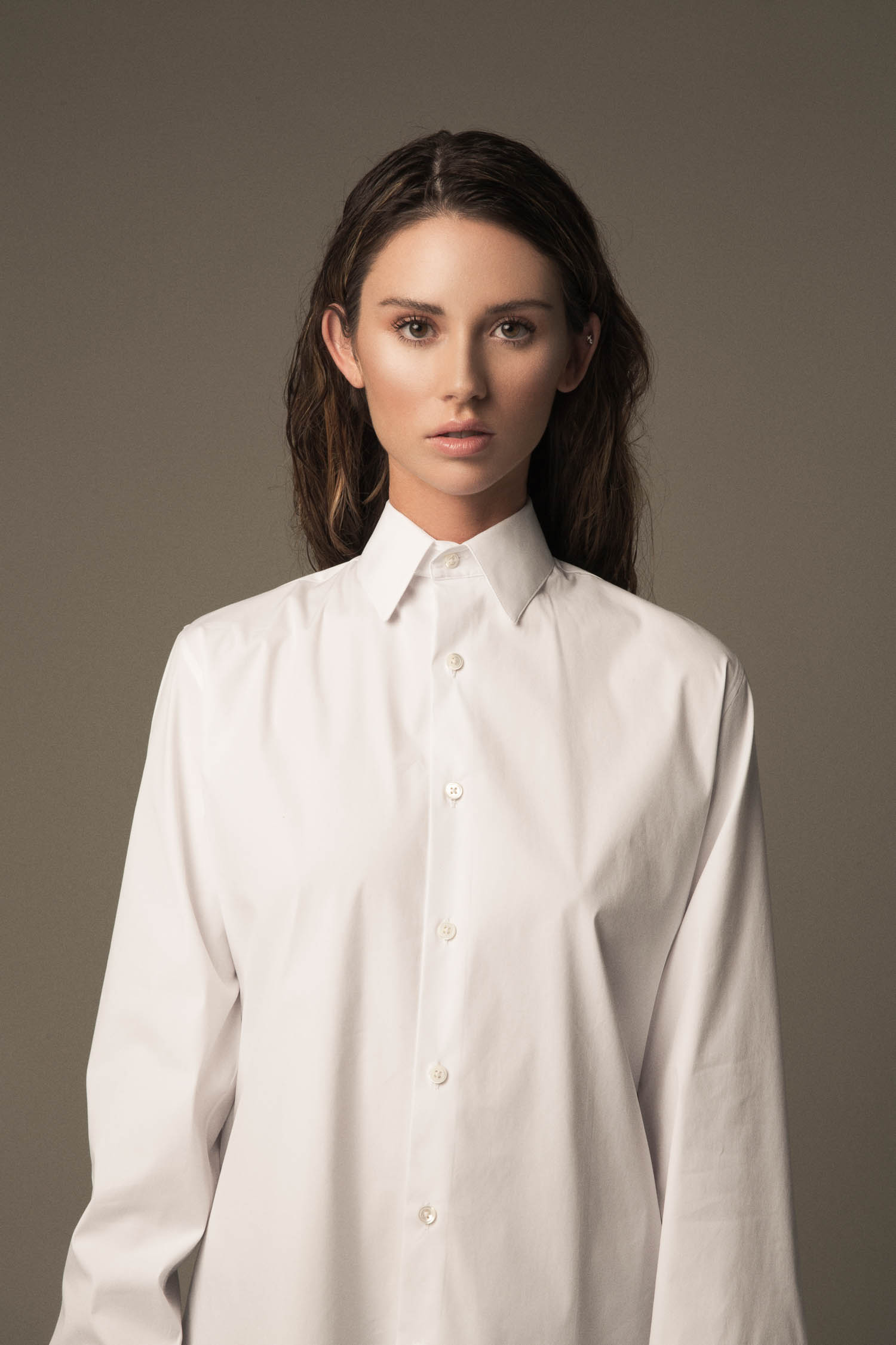 Portrait of a woman in a white men's dress shirt.