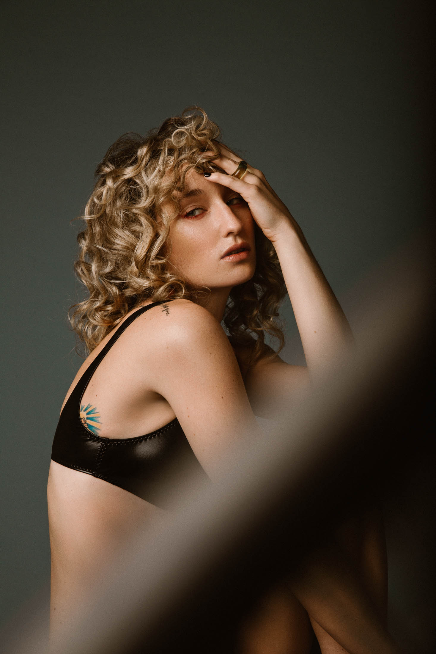 Curly hair blonde model wearing leather bikini top and DRIES VAN NOTEN ring