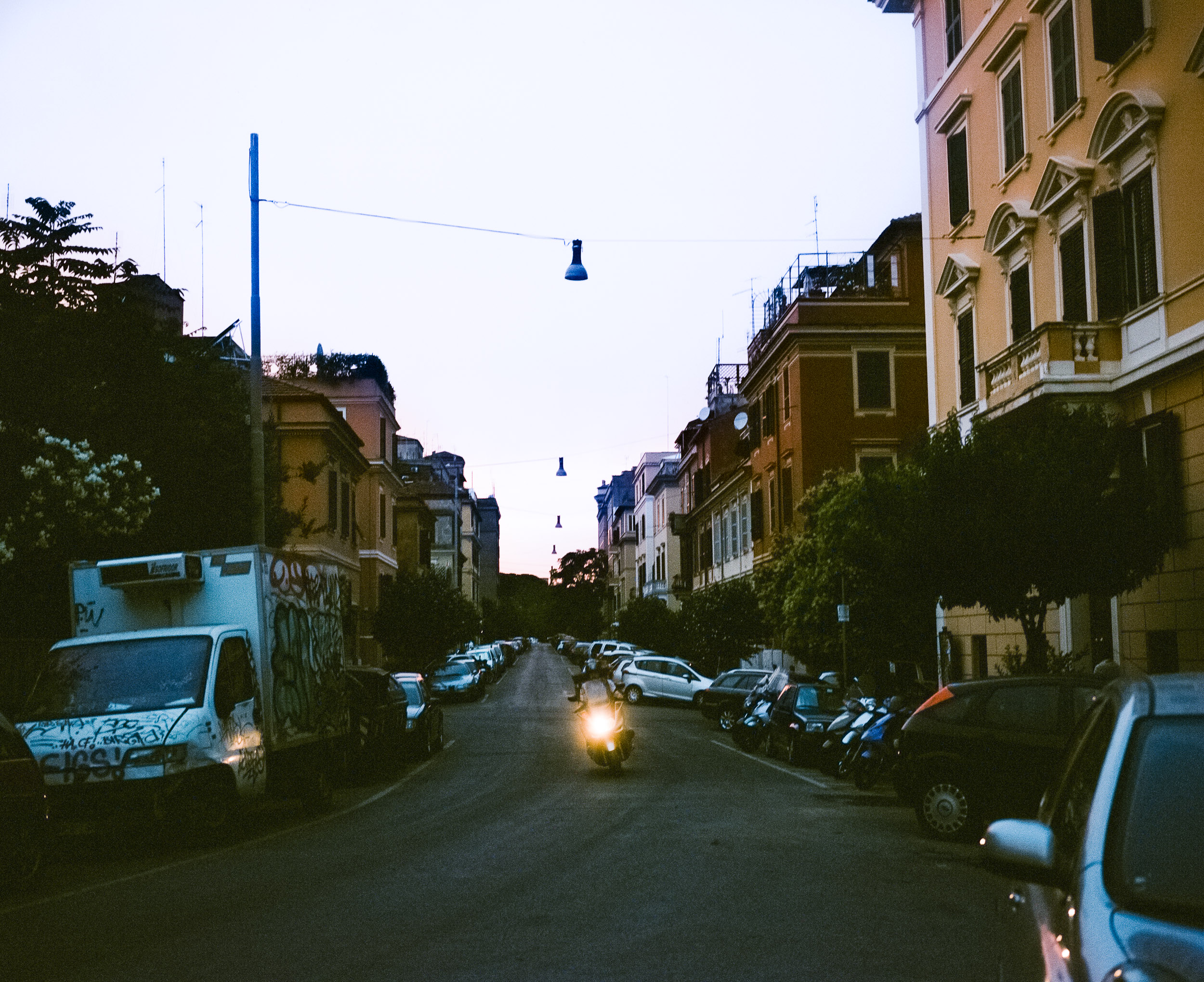 Motorcycle driving down the street in Rome with its headlight on