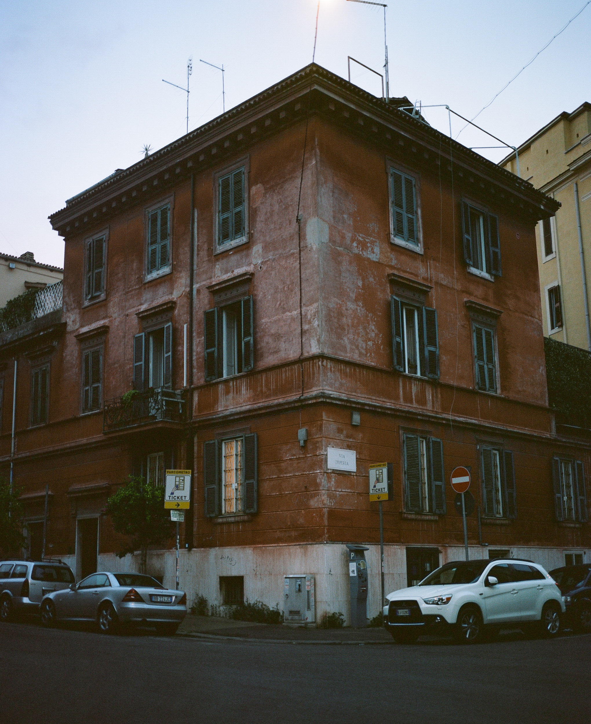 Red building in Rome, cars parked in front