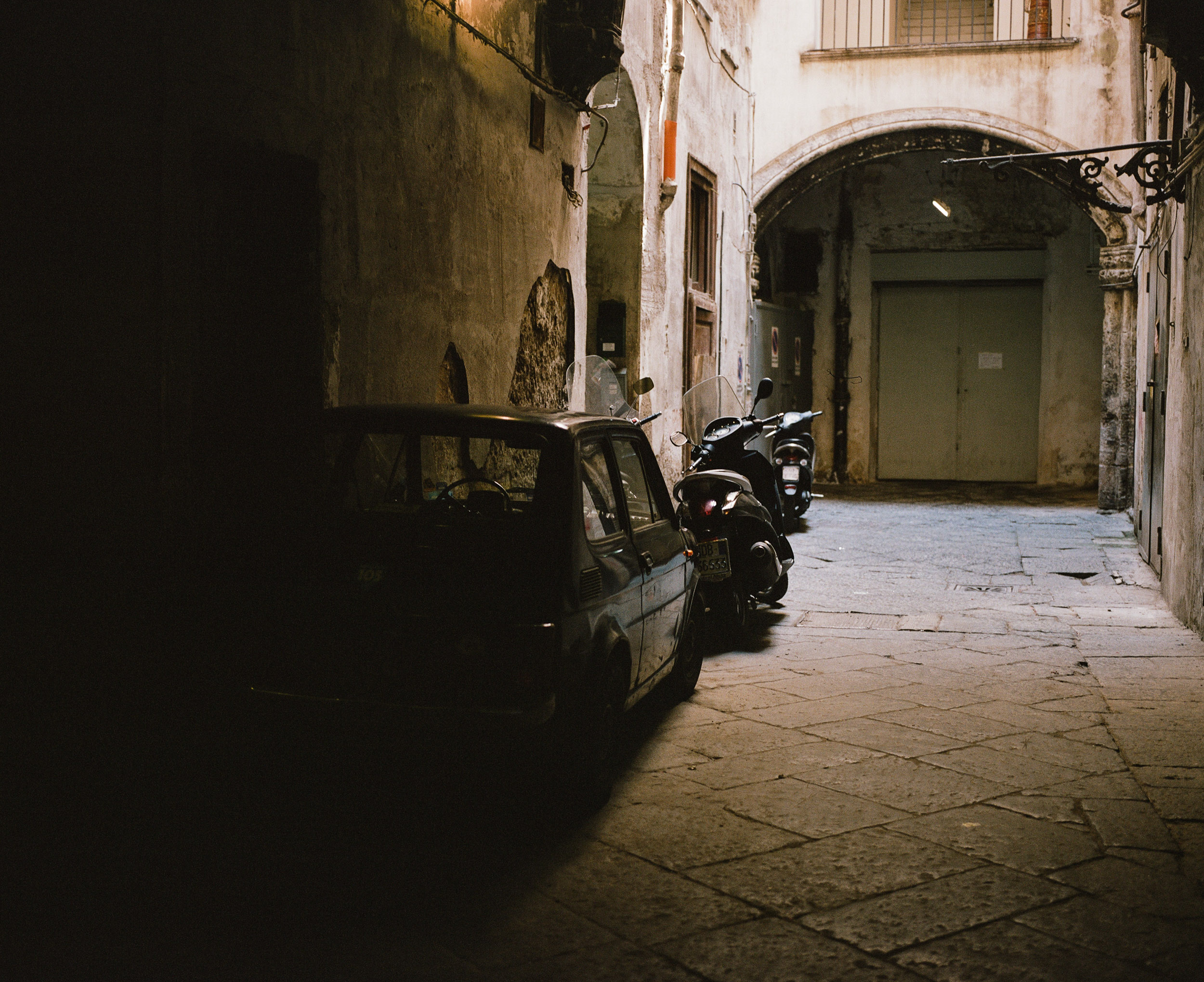 Parking courtyard in Naples, Italy with cars and scooters