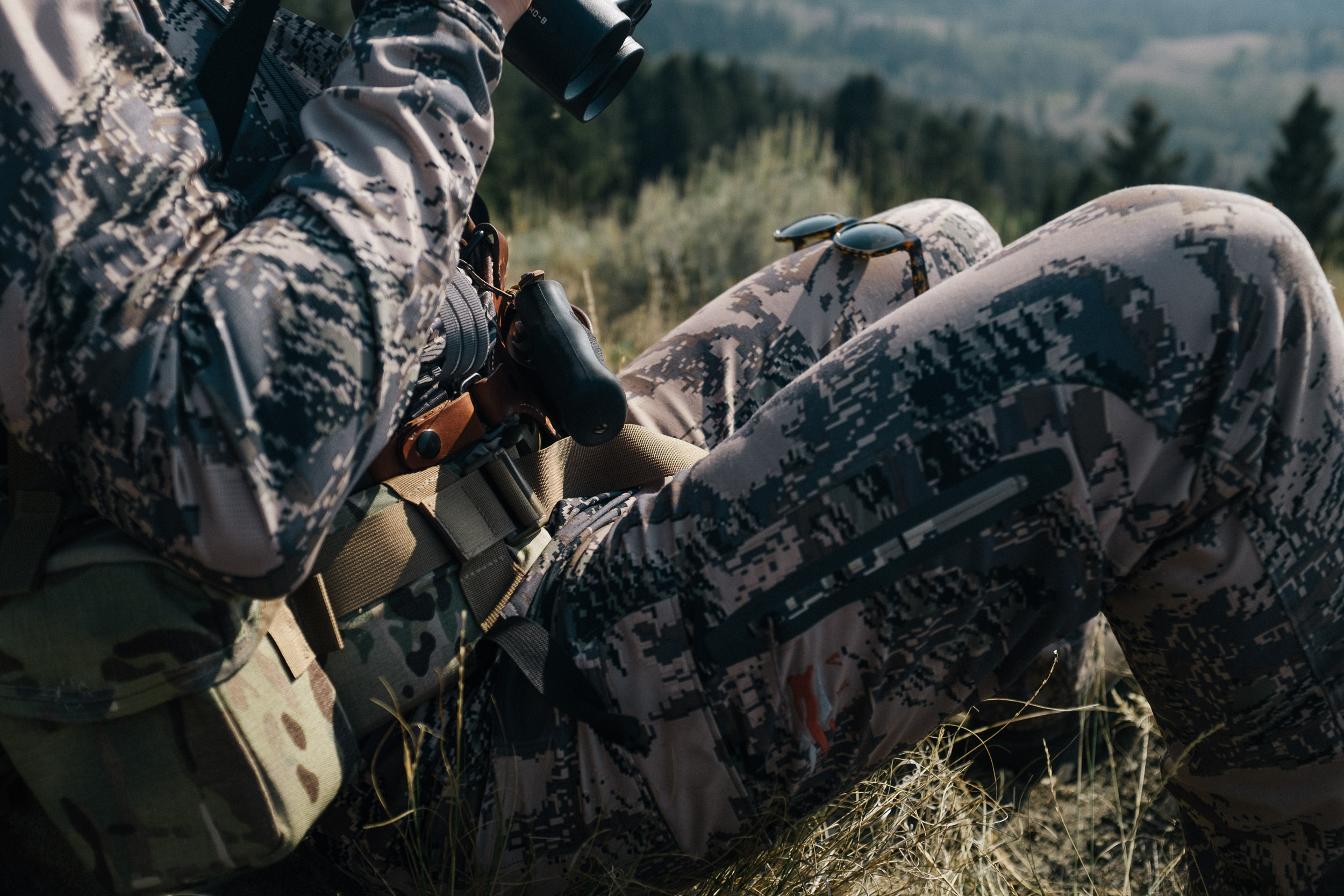 Gun in holster on hunters hip, sitka camoflage outfit