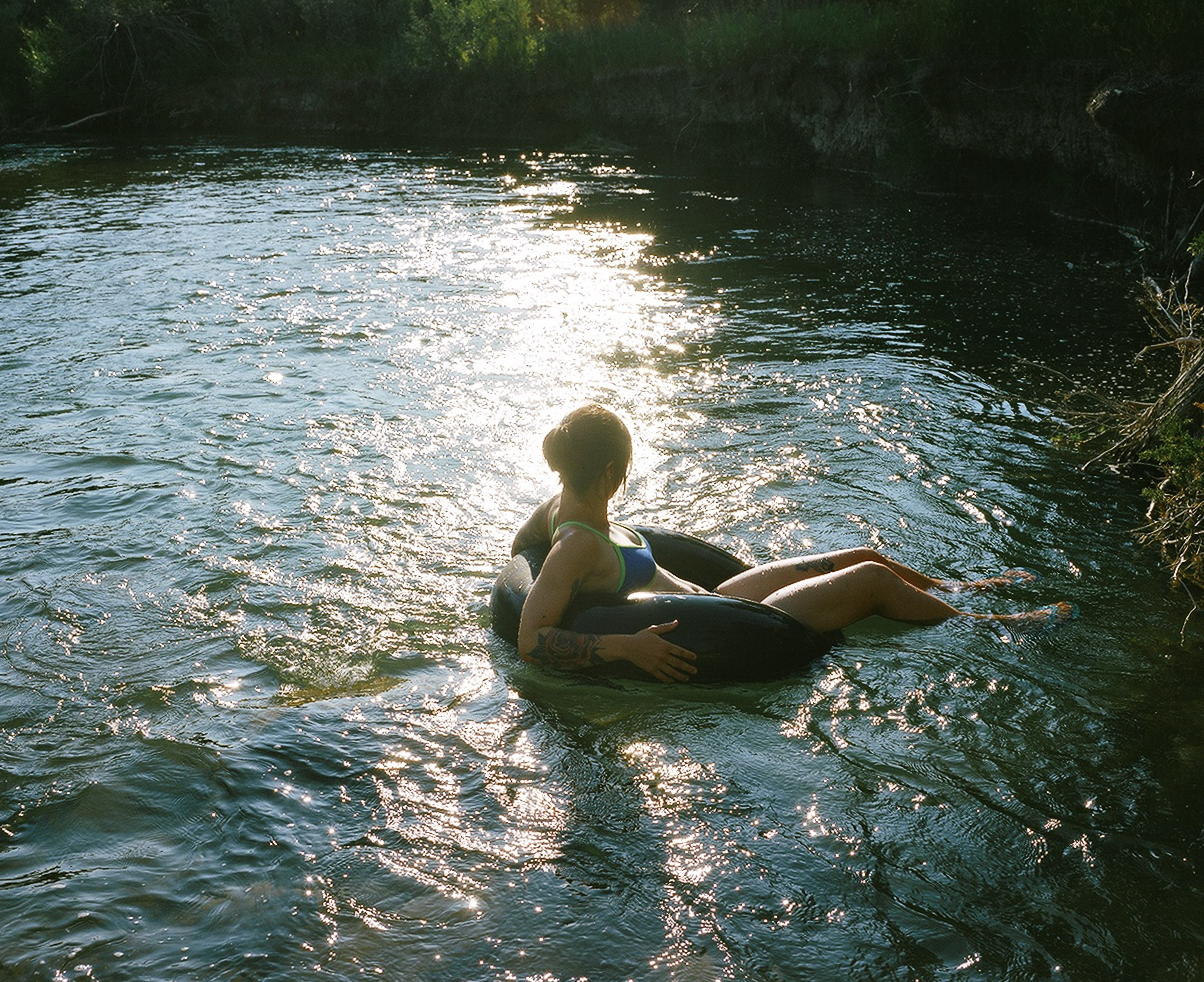 Woman floating in an innertube on a river in the glare of sunshineof 