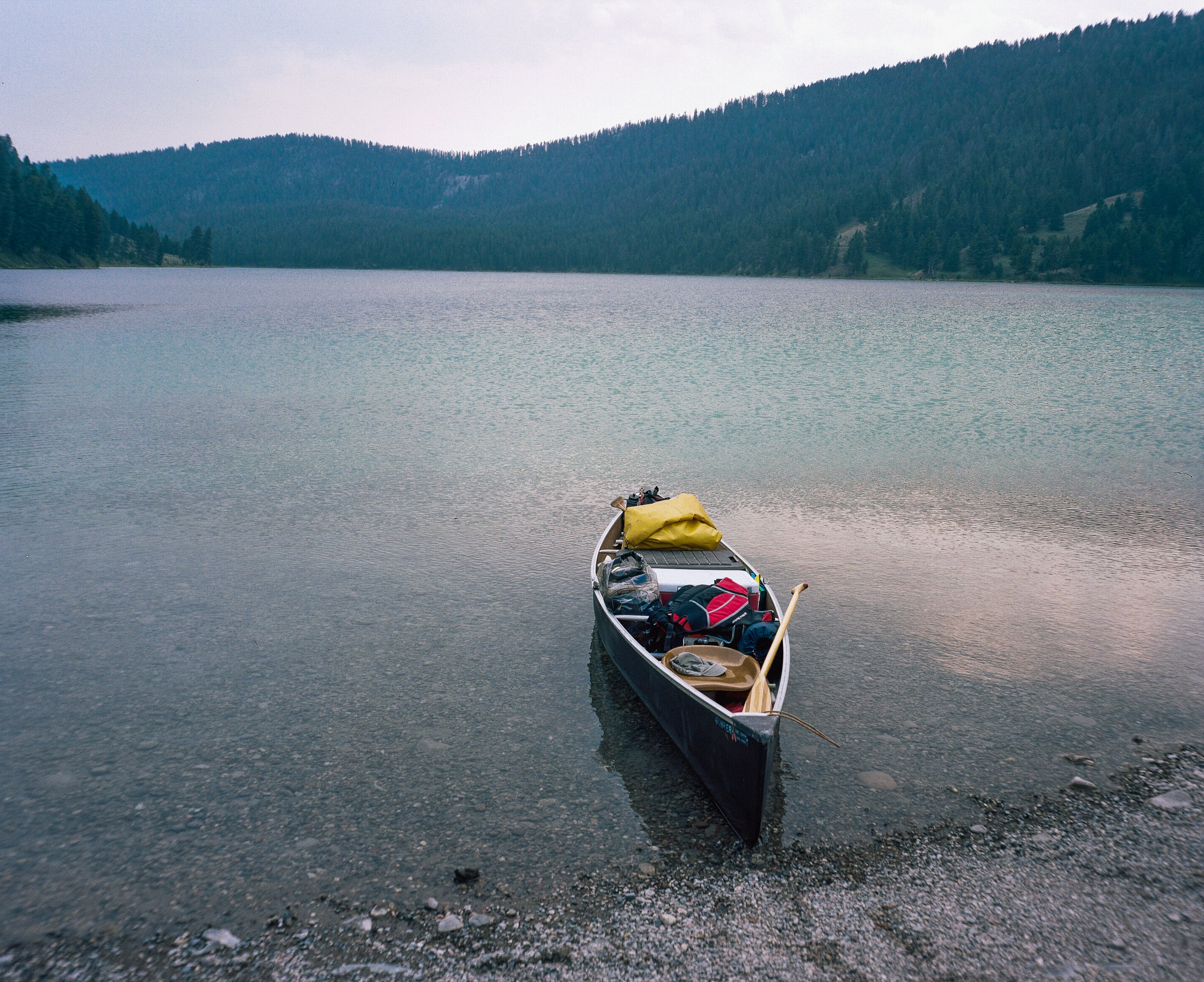 Fully loaded pack canoe in blue-green waters at Cliff Lake in Montana