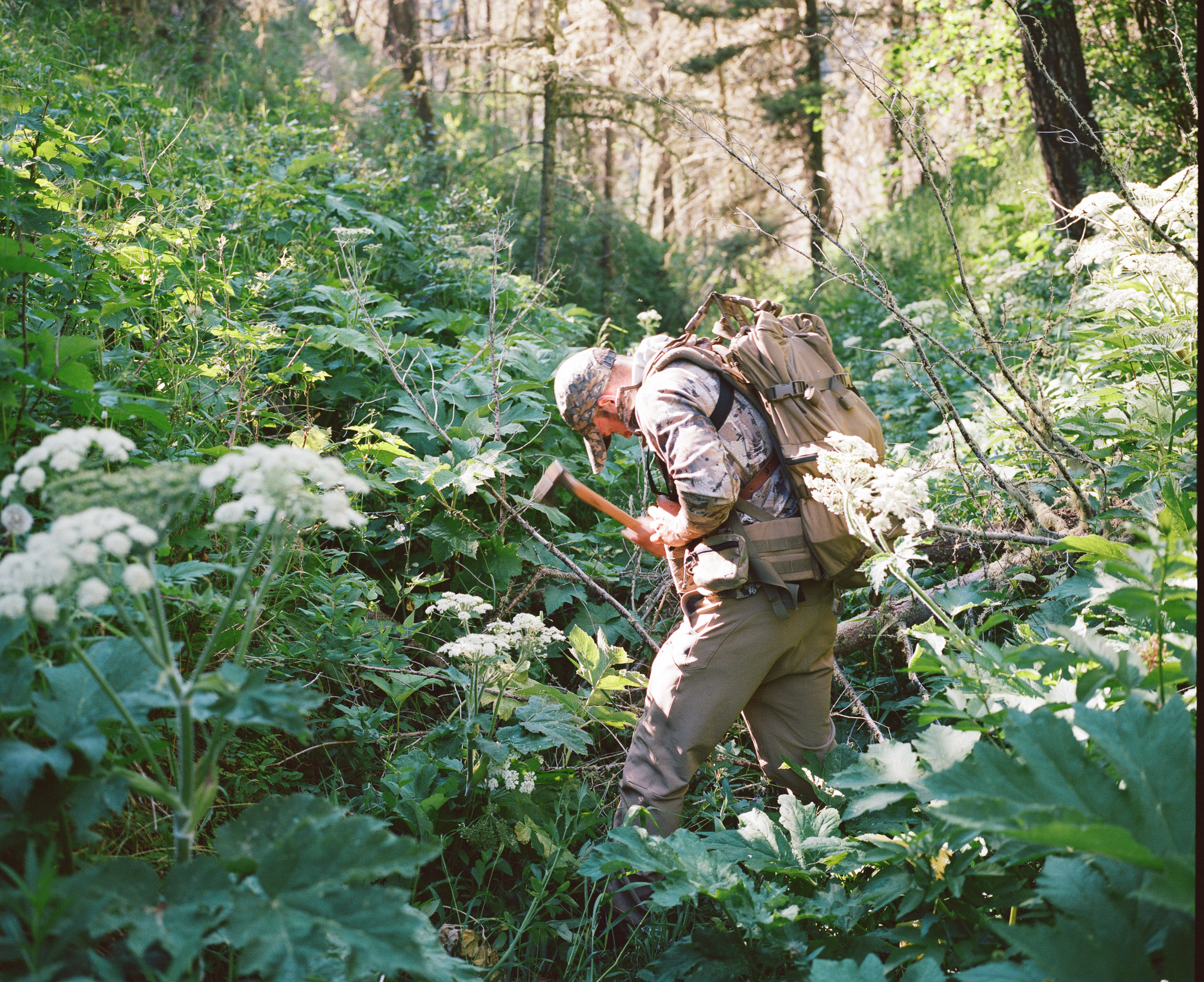 Hunter with a hatchet chopping and surrounded by grasses and flowers